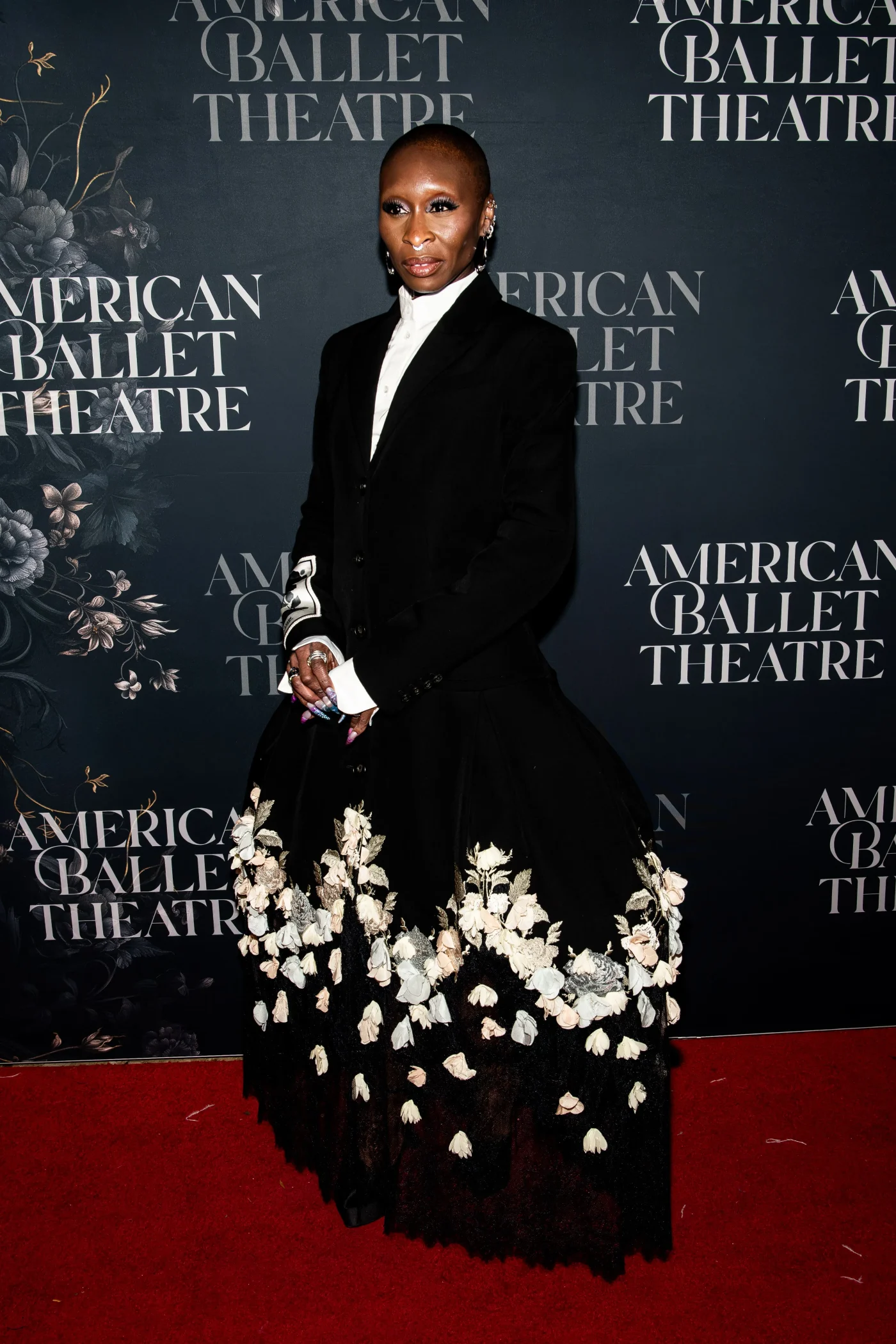 Cynthia Erivo on the red carpet at the American Ballet Theatre Fall Gala, wearing a black jacket and a black skirt adorned with floral appliqués.