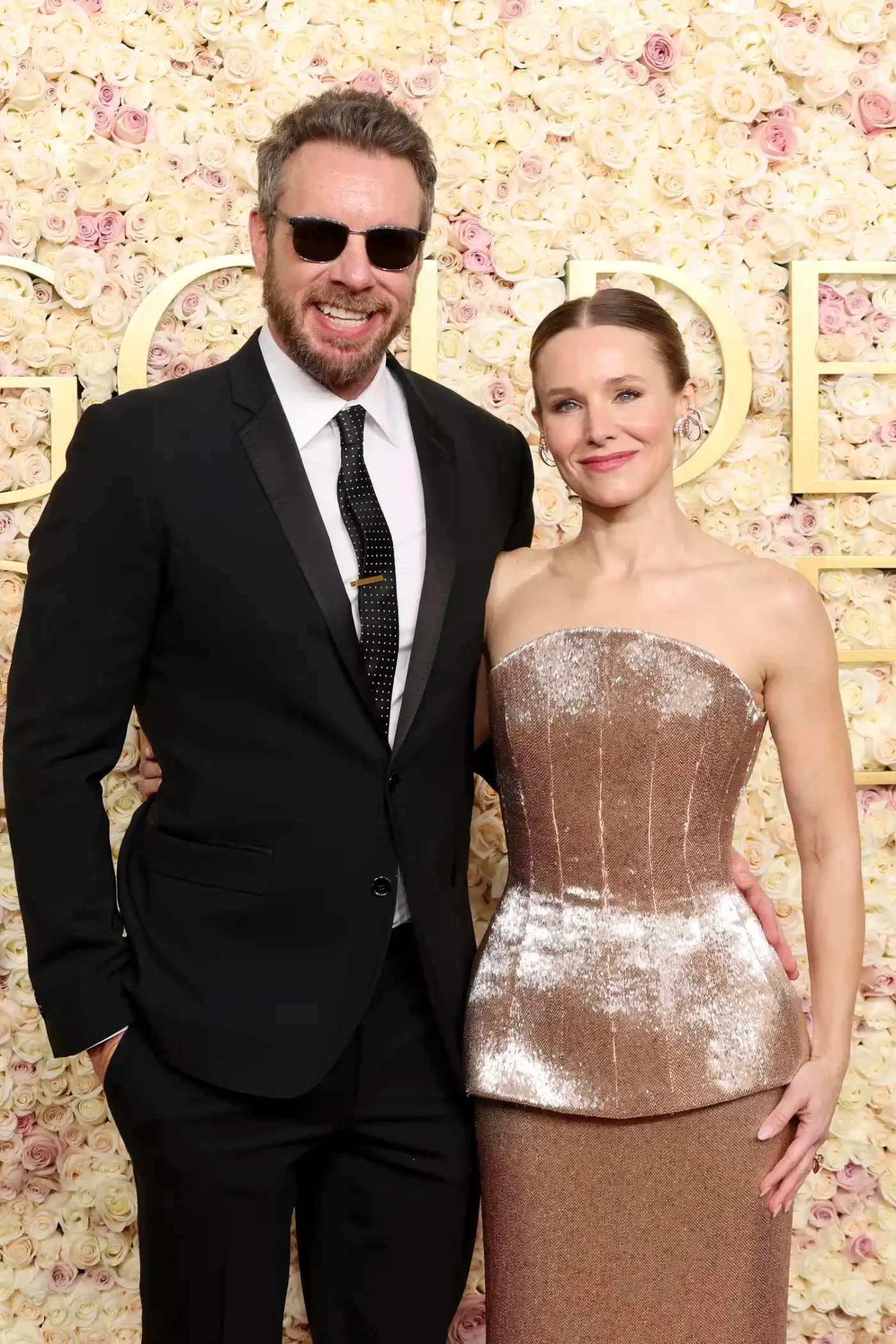 Dax Shepard and Kristen Bell posing together at an event standing in front of a floral backdrop