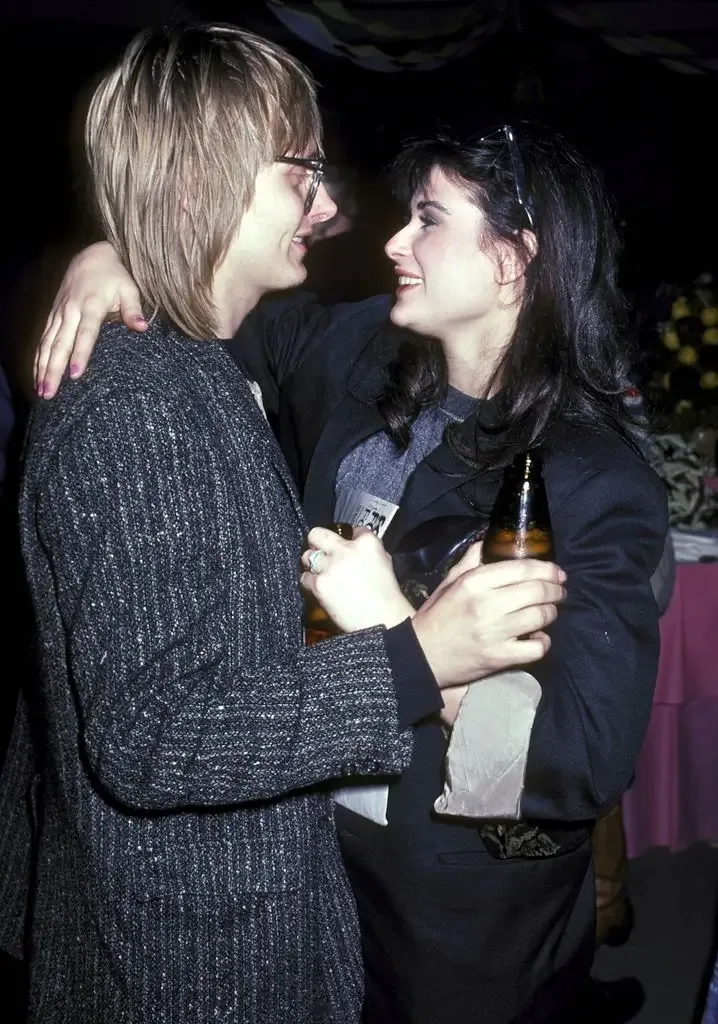 Demi Moore and Freddie Moore embrace and smile at each other while holding beer bottles at a party.