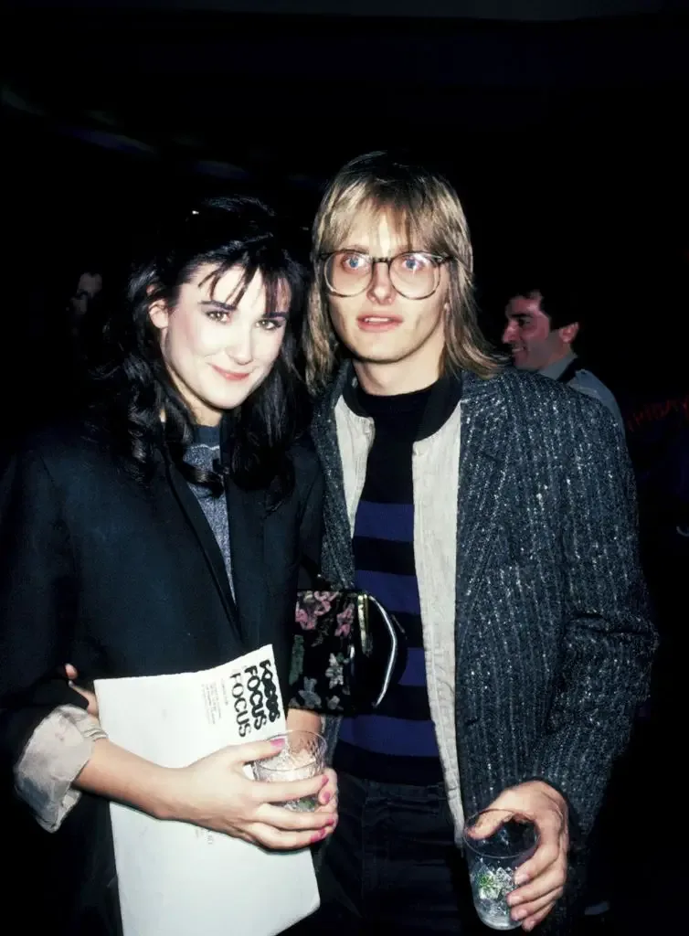 Demi Moore and Freddy Moore pose together at a party, both holding drinks, with Demi holding a Focus magazine