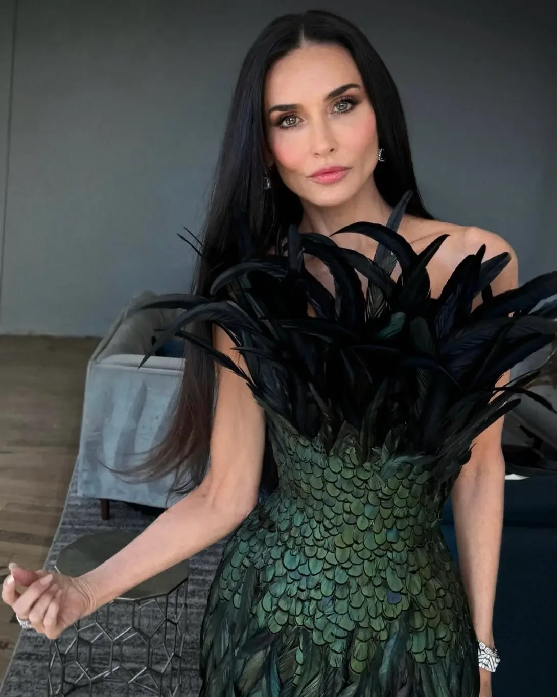 Demi Moore wearing a structured green and black feathery dress.