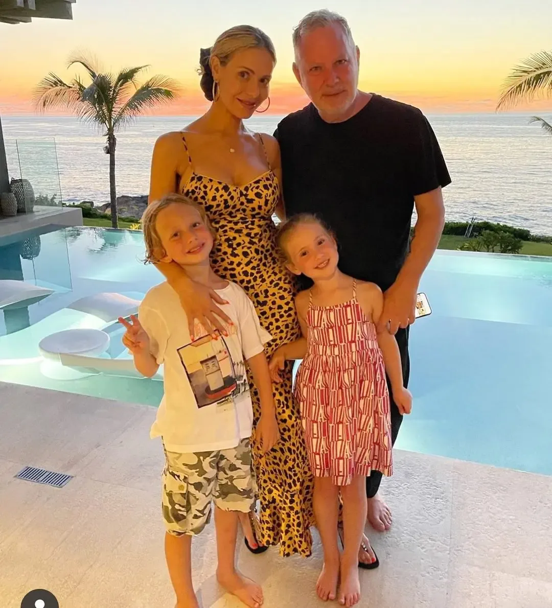 Dorit and Paul Kemsley posing with their two young children by a swimming pool at sunset.