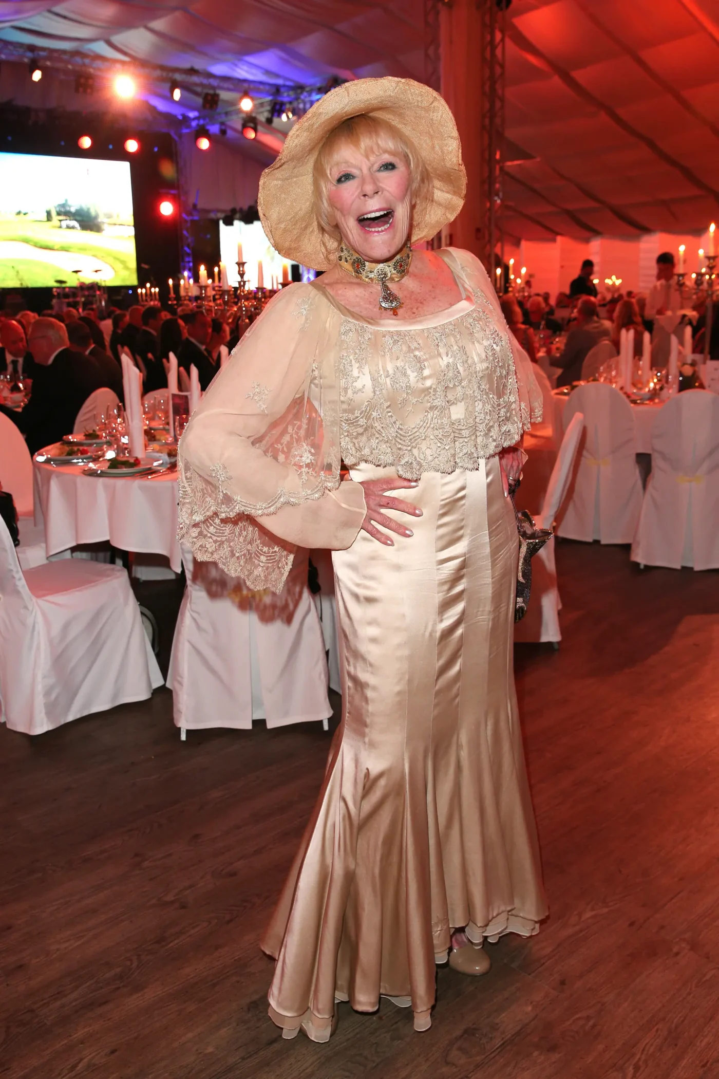 Elke Sommer wearing a cream gown and a wide-brimmed straw hat at the EAGLES Praesidenten Golf Cup Gala Evening.