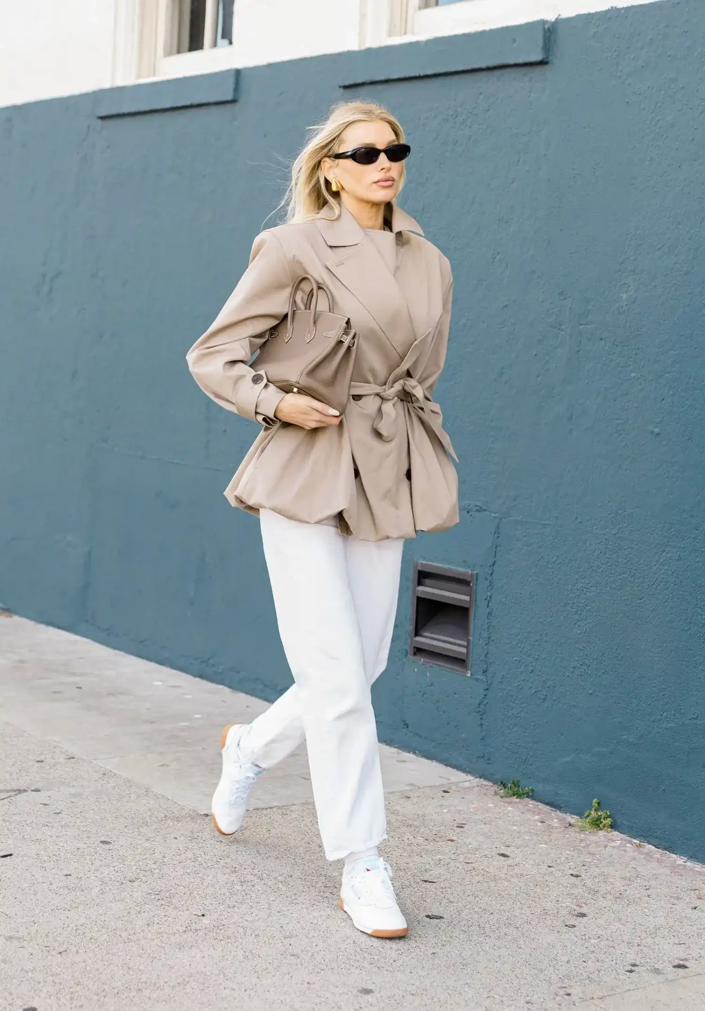 Elsa Hosk walking on a street wearing a blazer pants and sneakers