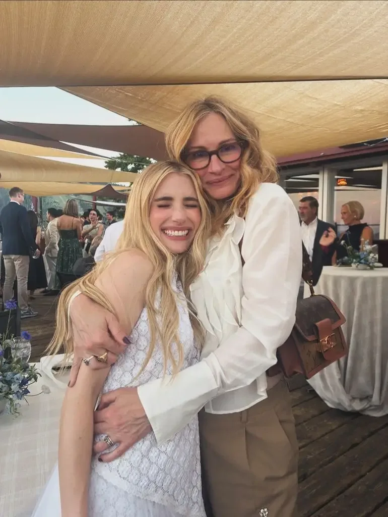 Emma Roberts with her eyes closed and smiling as she is hugged by Julia Roberts