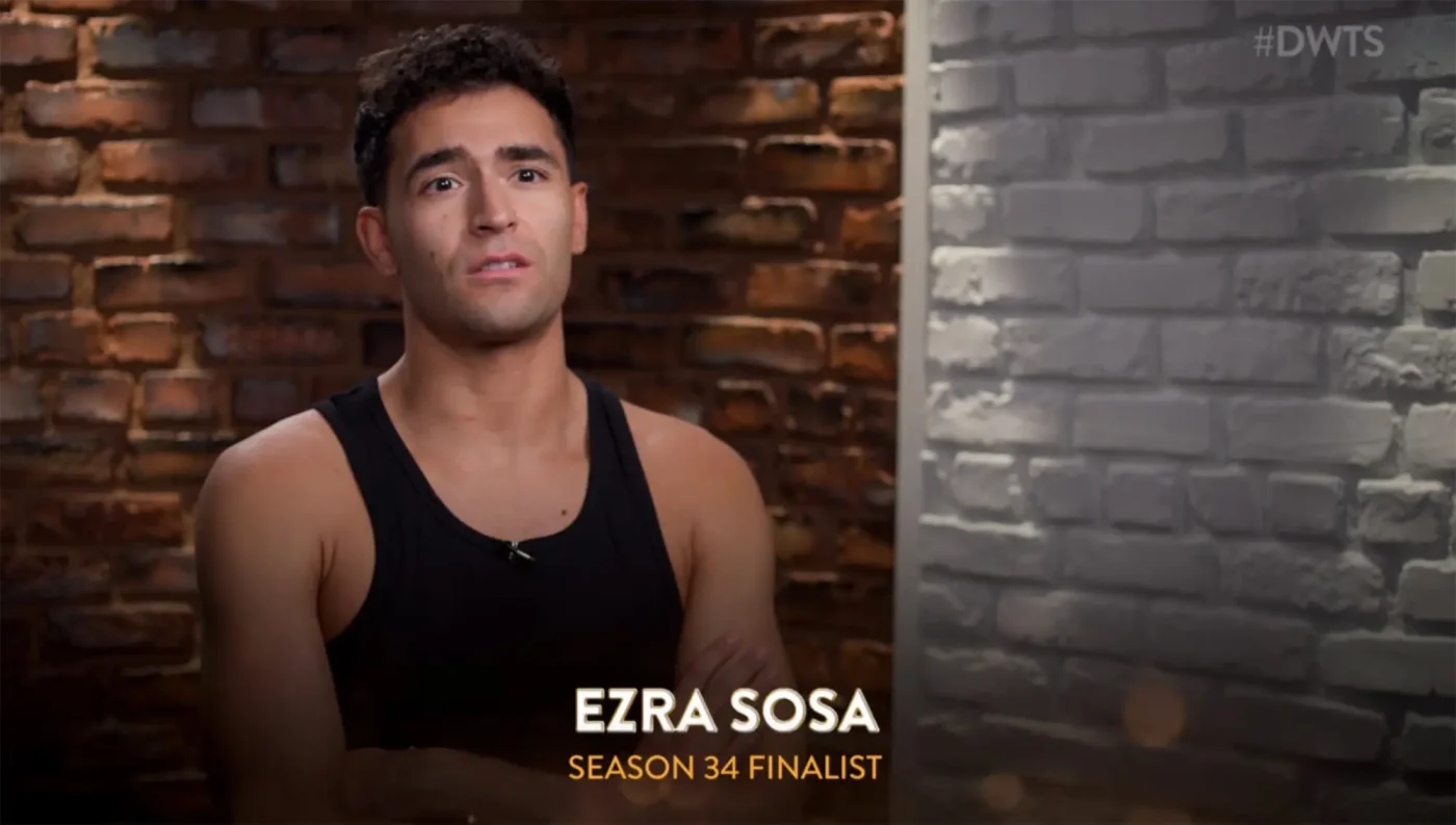 Ezra Sosa in a black tank top with a brick wall background.