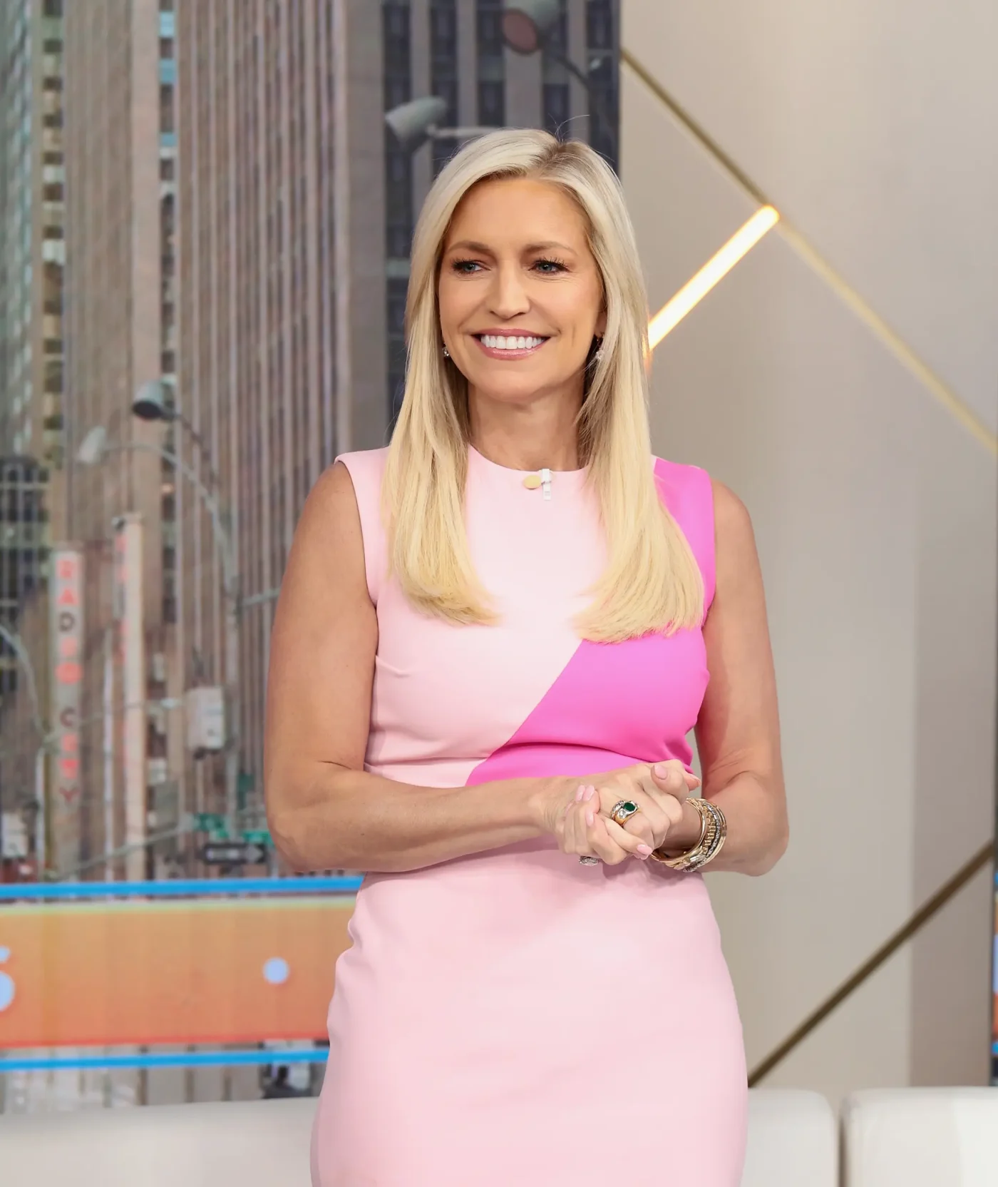 Fox News Channel Host Ainsley Earhardt smiling in a pink dress in a television studio.