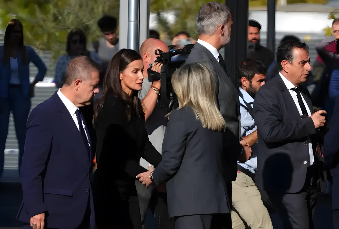 Group of people, including Emiliano García-Page in a gray suit, walking through a crowd.