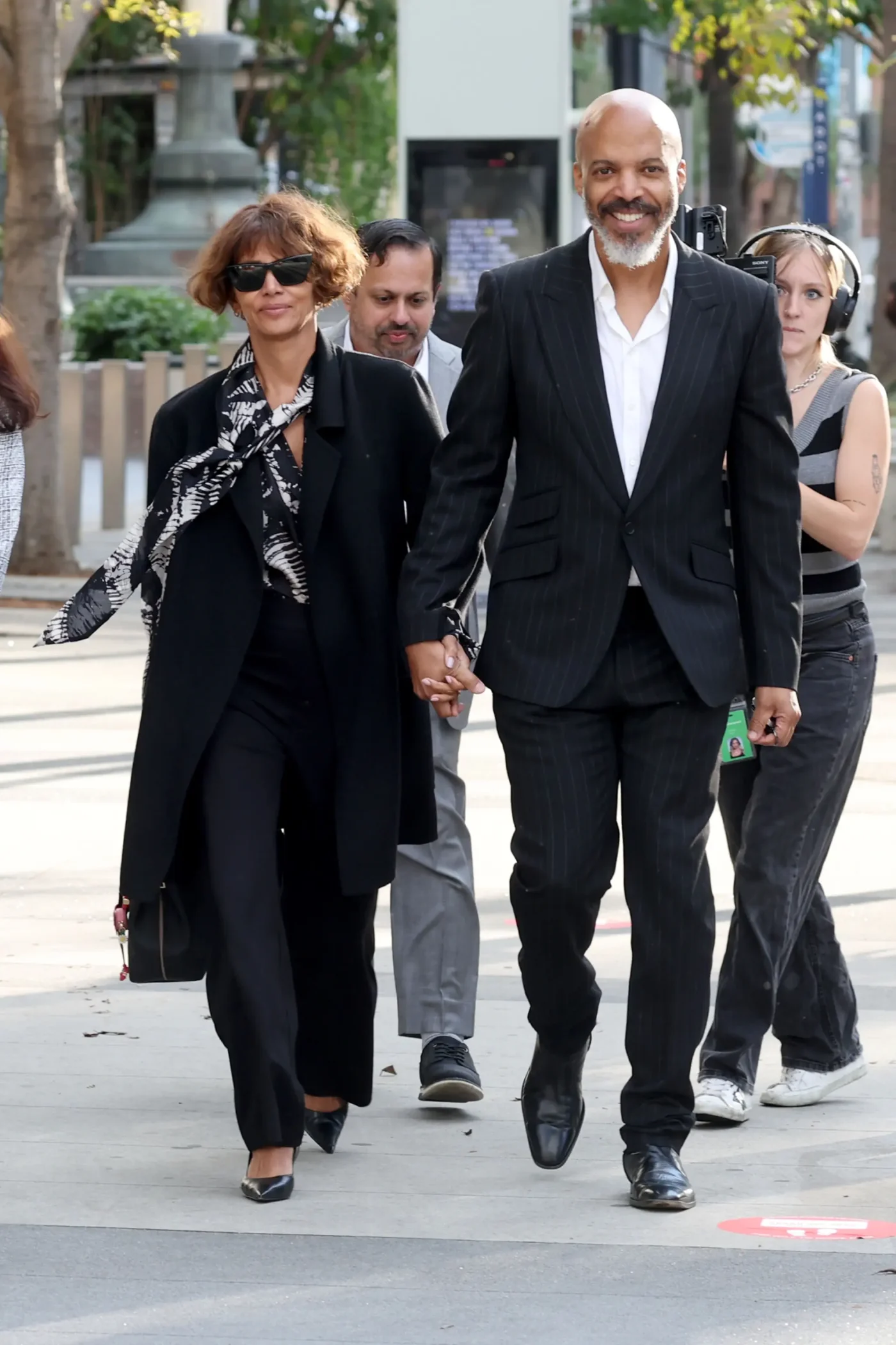 Halle Berry and Van Hunt hold hands while smiling as they walk outside.