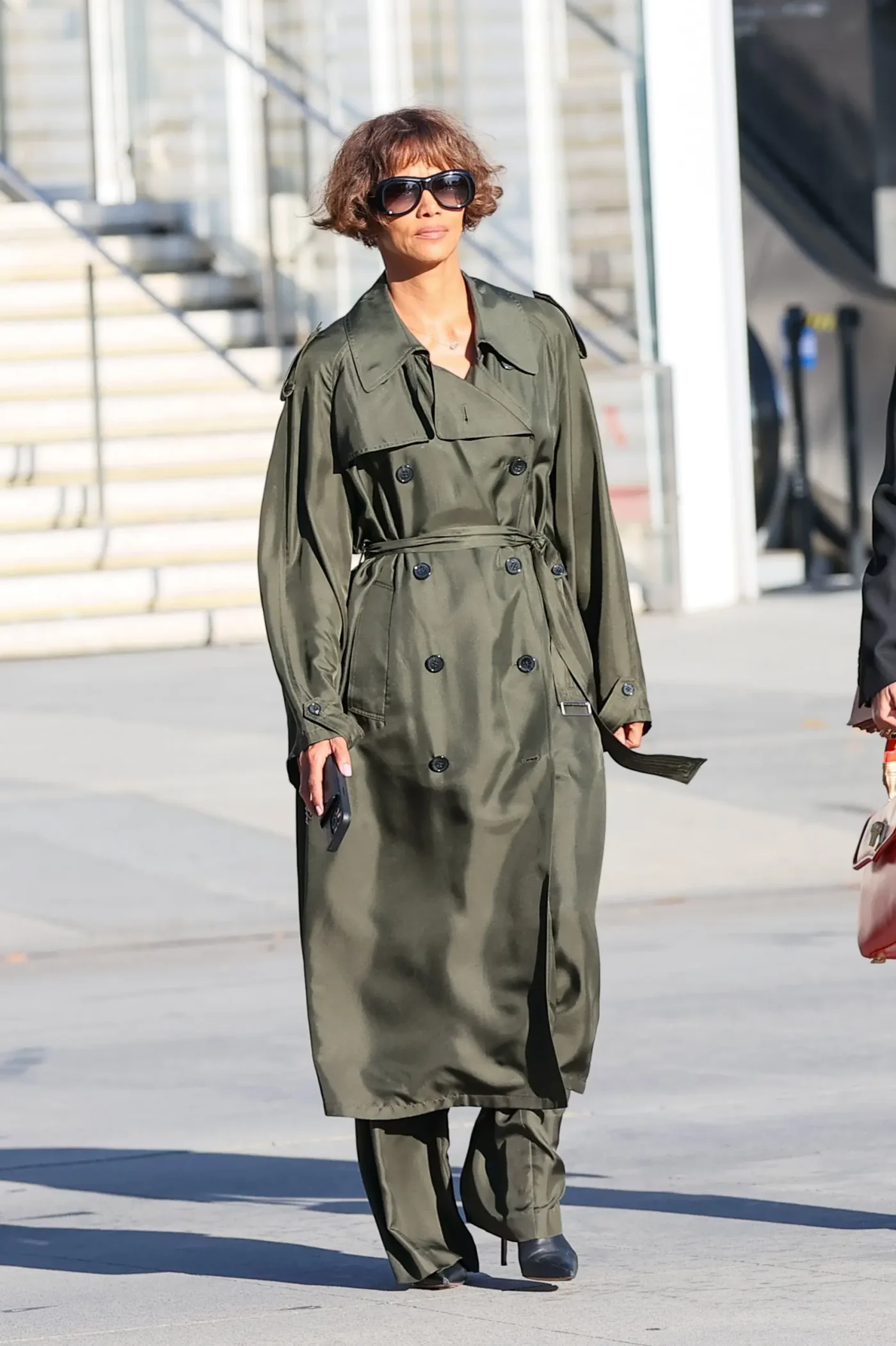 Halle Berry arrives for a custody hearing wearing a long, olive green trench coat and sunglasses.