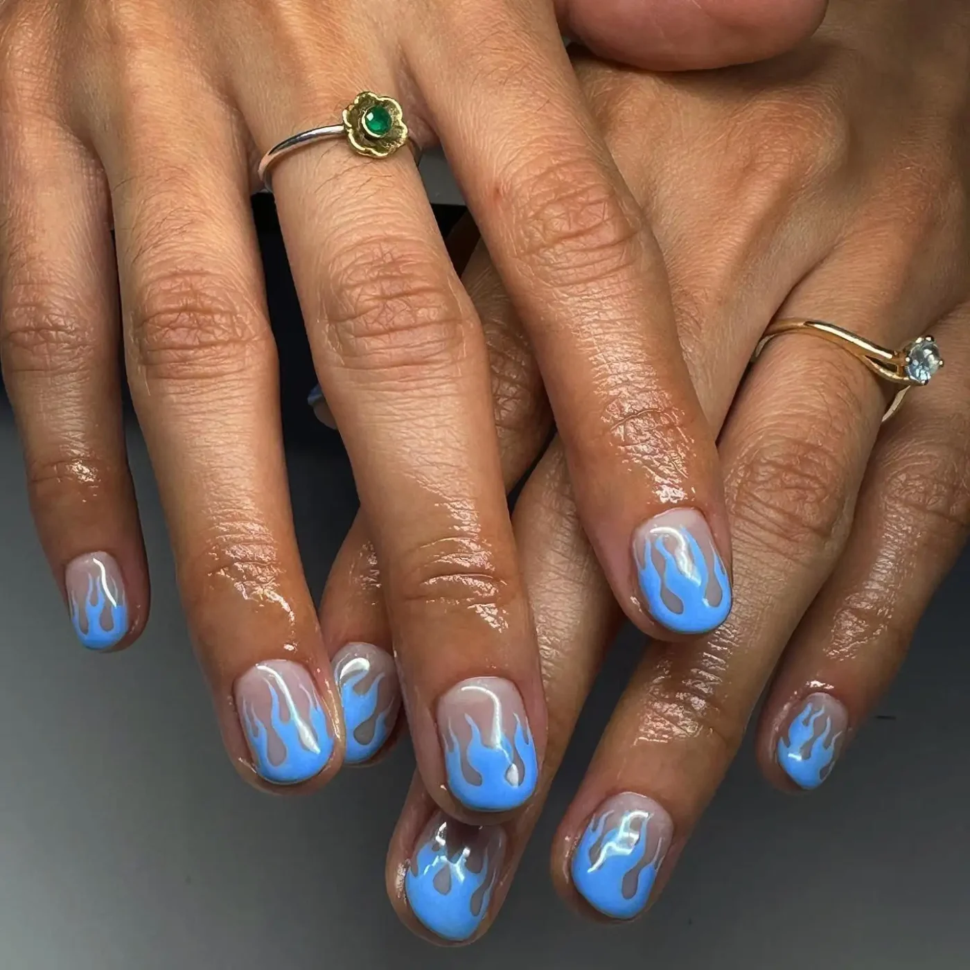 Hands with blue flame nail art and rings
