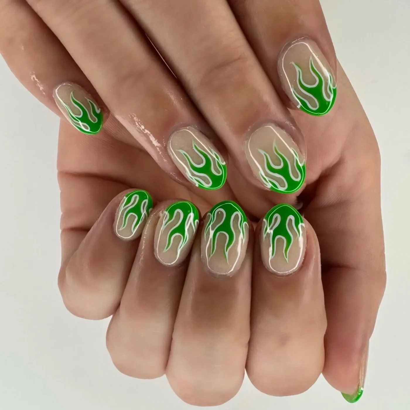 Hands with fingernails having green flame nail art design