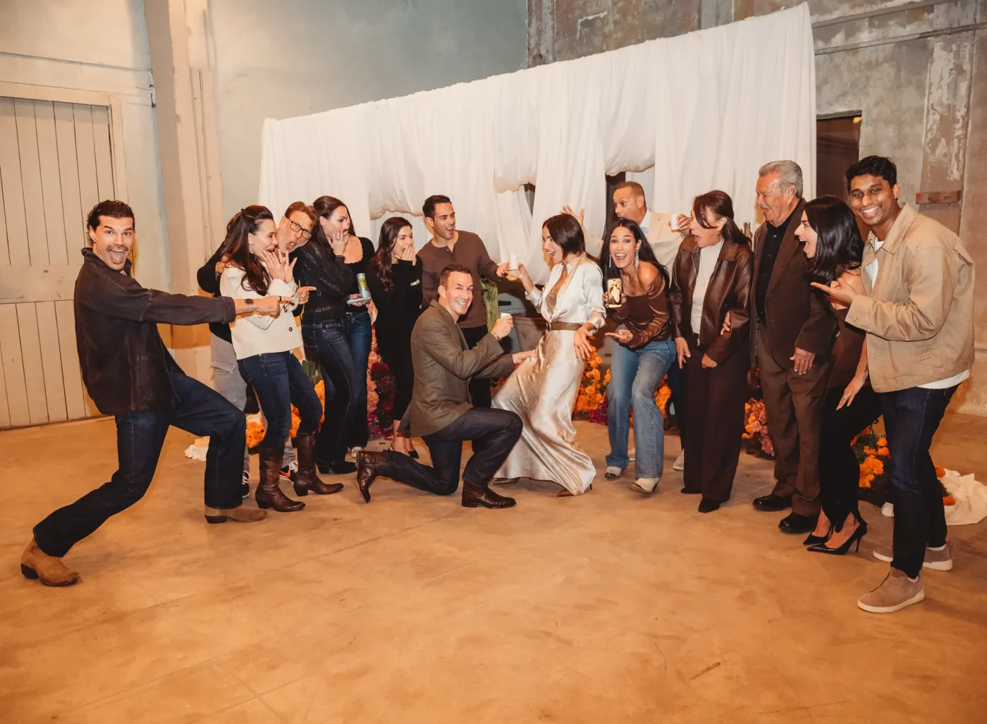 Harvey Spevak is on one knee proposing to Bianca Peters in front of a group of cheering friends.
