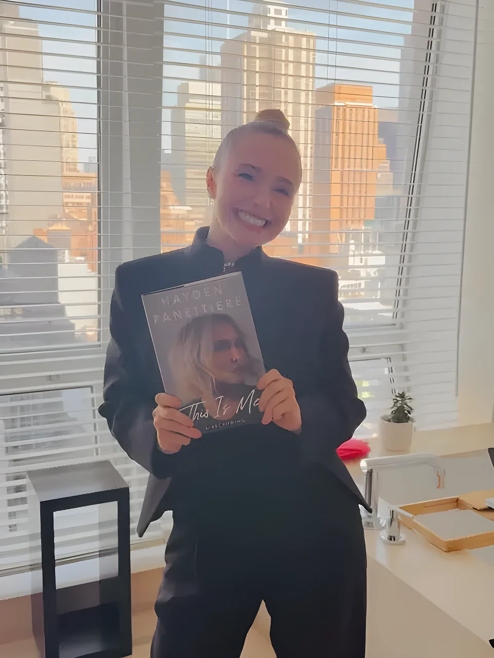 Hayden Panettiere smiling and holding a book titled
