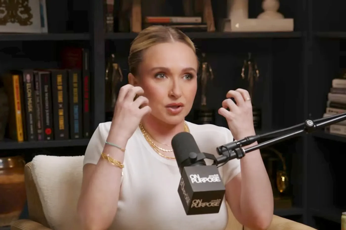 Hayden Panettiere speaking into a podcast microphone while gesturing with her hands.