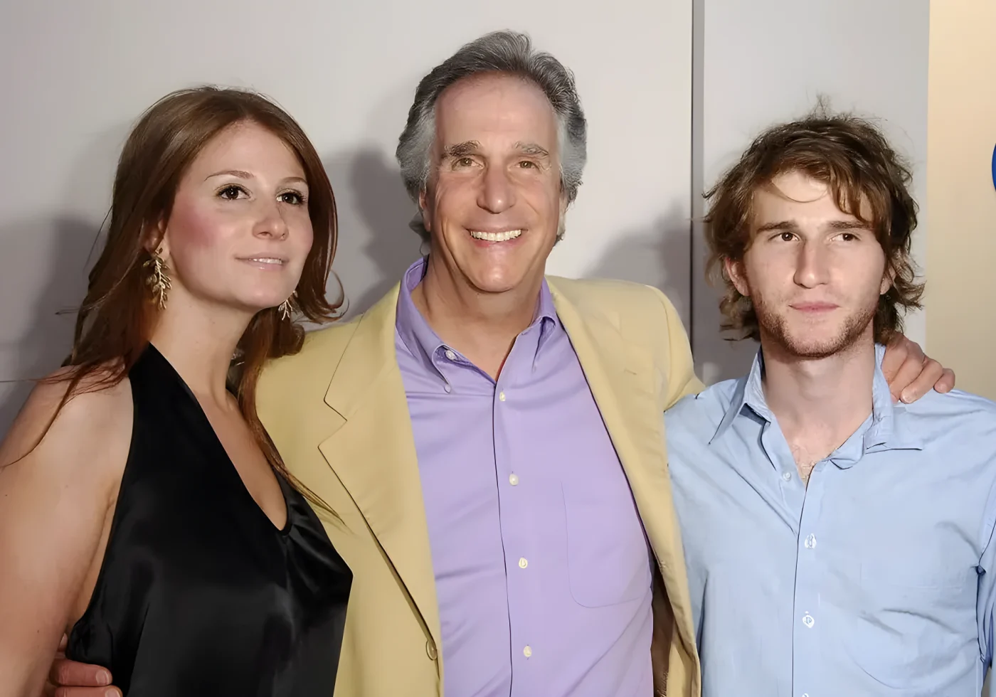 Henry Winkler, in a yellow jacket and lilac shirt, smiles with his arms around his daughter Zoe, in a black halter dress, and his son Max, in a light blue shirt.