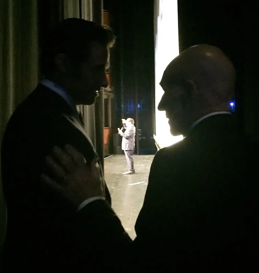 Hugh Jackman and Patrick Stewart in silhouettes, facing each other backstage.