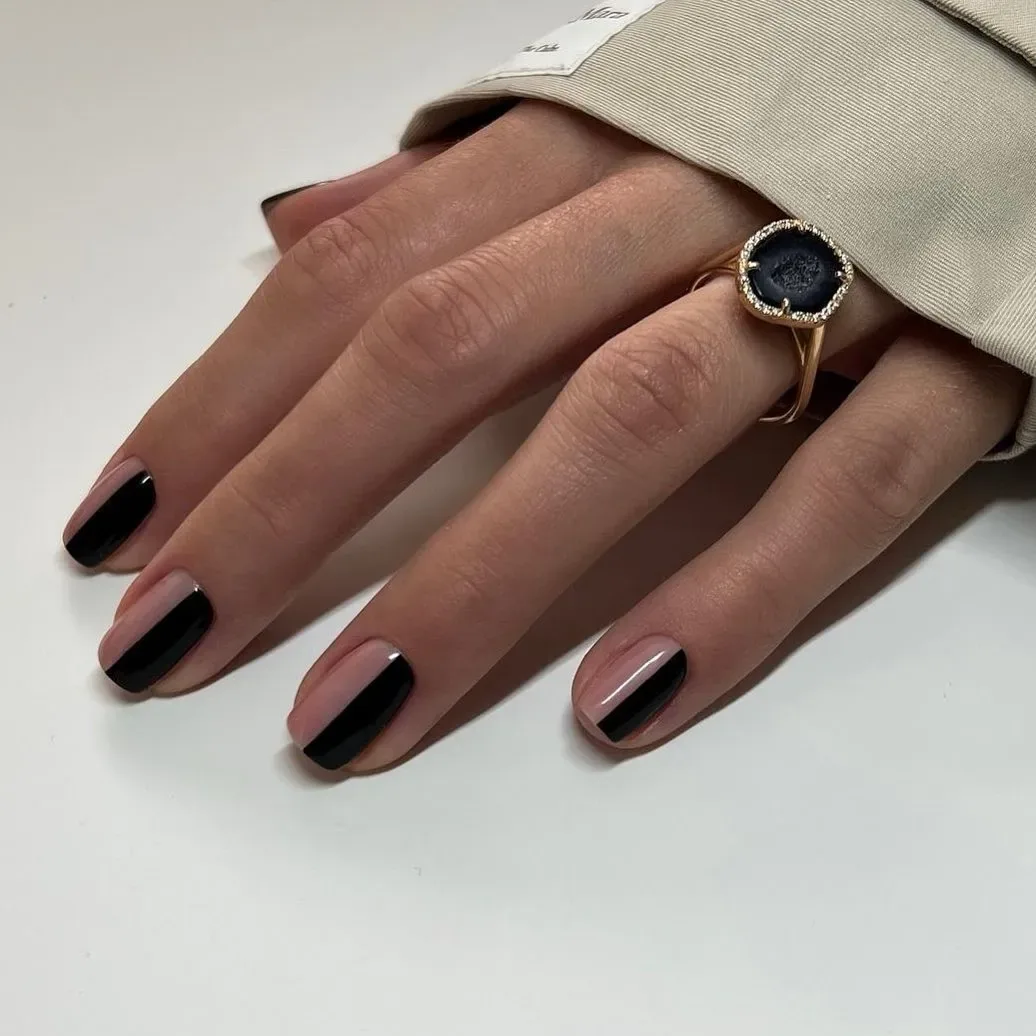 Human hand with black and pink nail polish and a ring wearing a beige sleeve