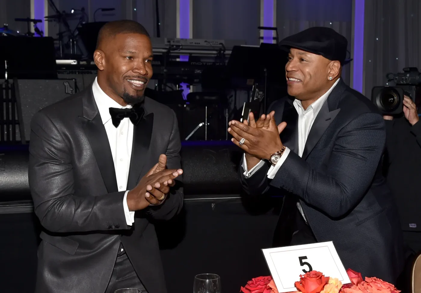 Jamie Foxx and LL Cool J clapping and smiling at a formal event