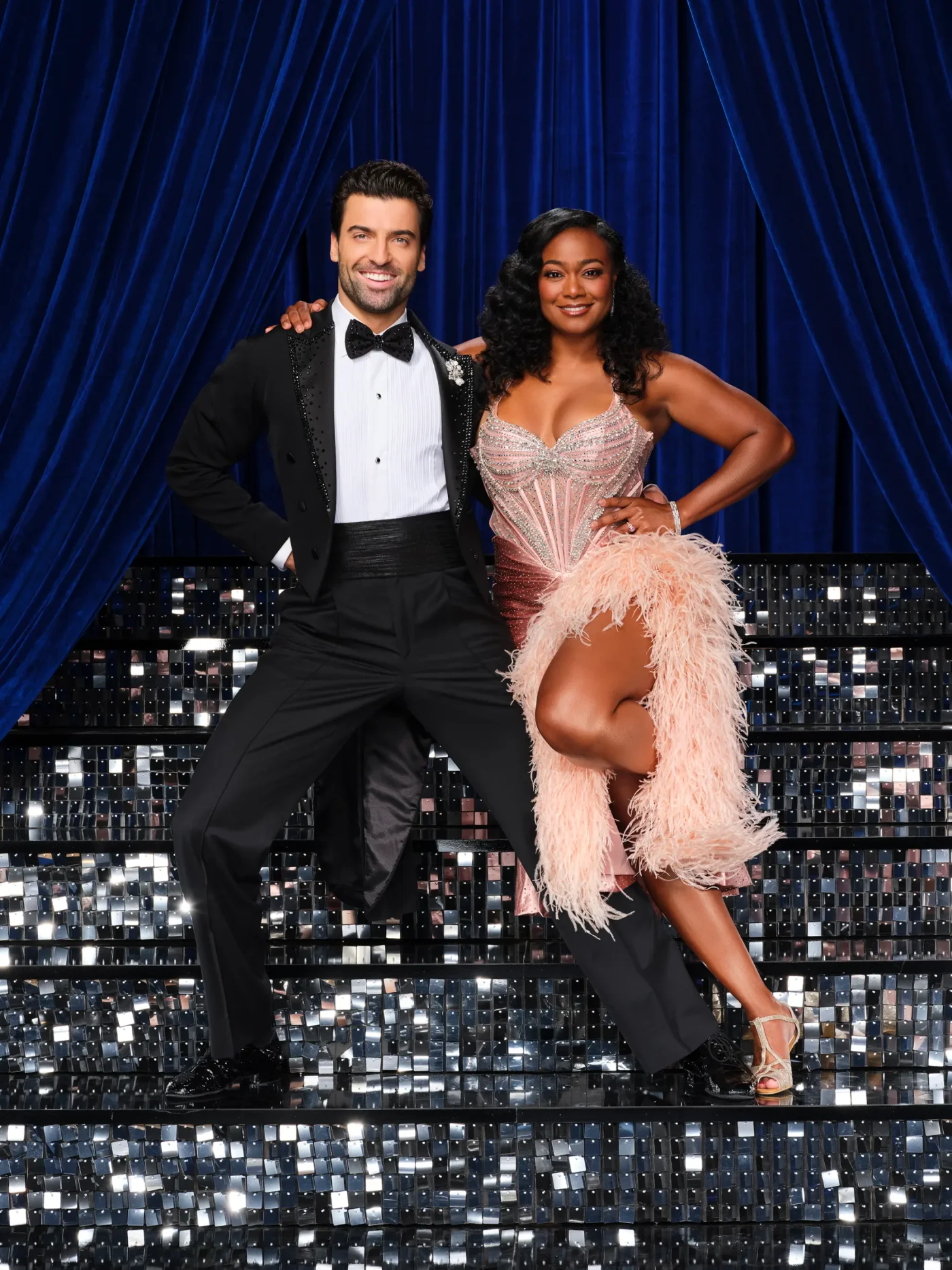 Jan Ravnik and Tatyana Ali pose on a staircase with a blue curtain backdrop.
