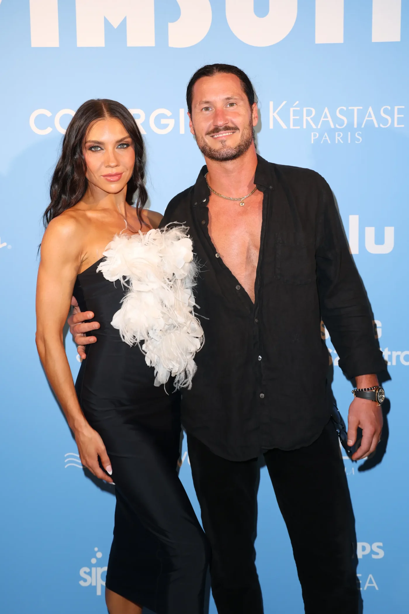 Jenna Johnson and Val Chmerkovskiy pose together on a blue-carpeted event.