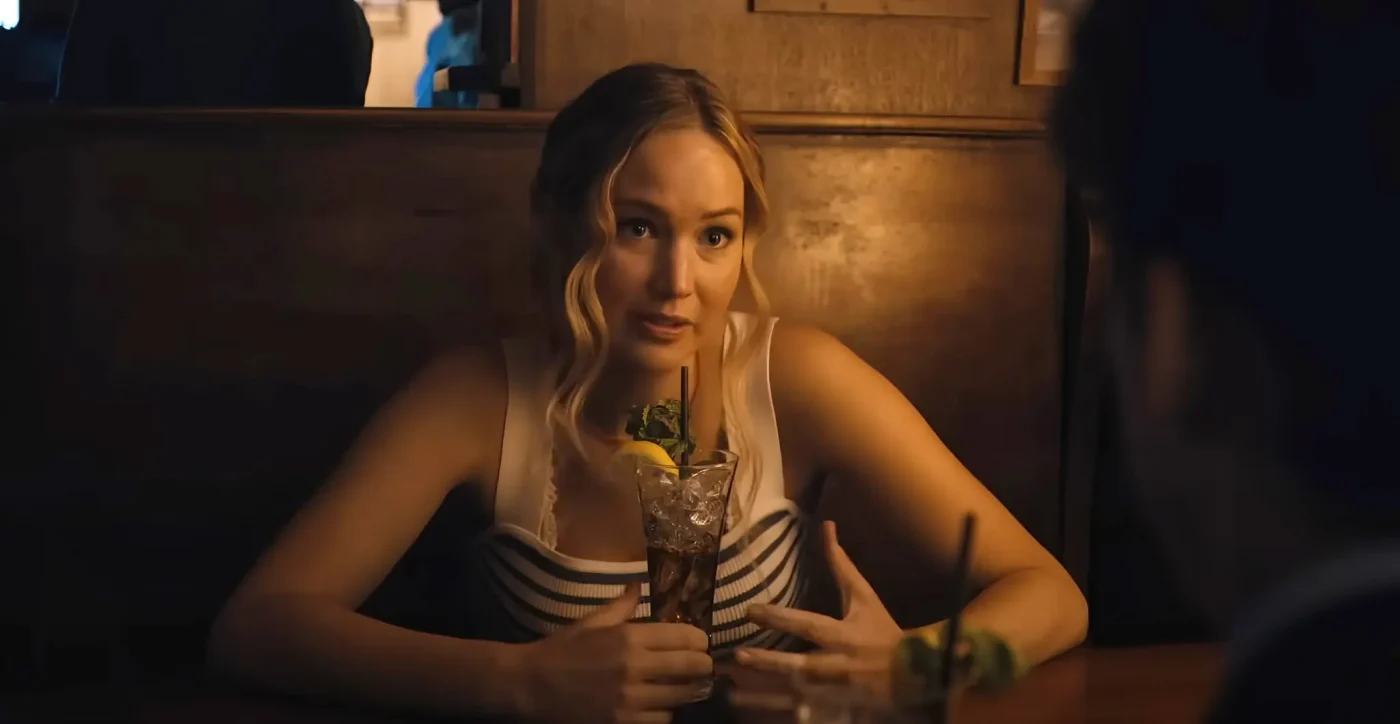 Jennifer Lawrence as Maddie Barker in No Hard Feelings sitting in a booth and talking to Andrew Barth Feldman.