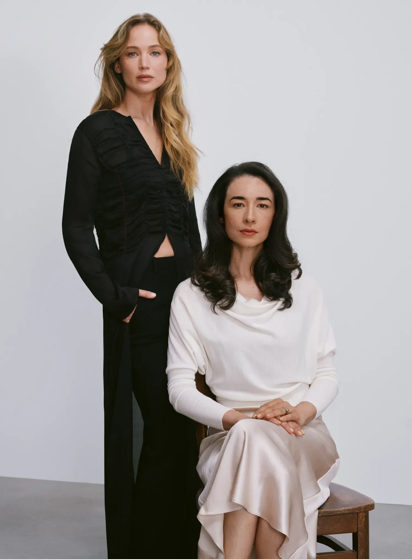 Jennifer Lawrence standing next to a seated woman