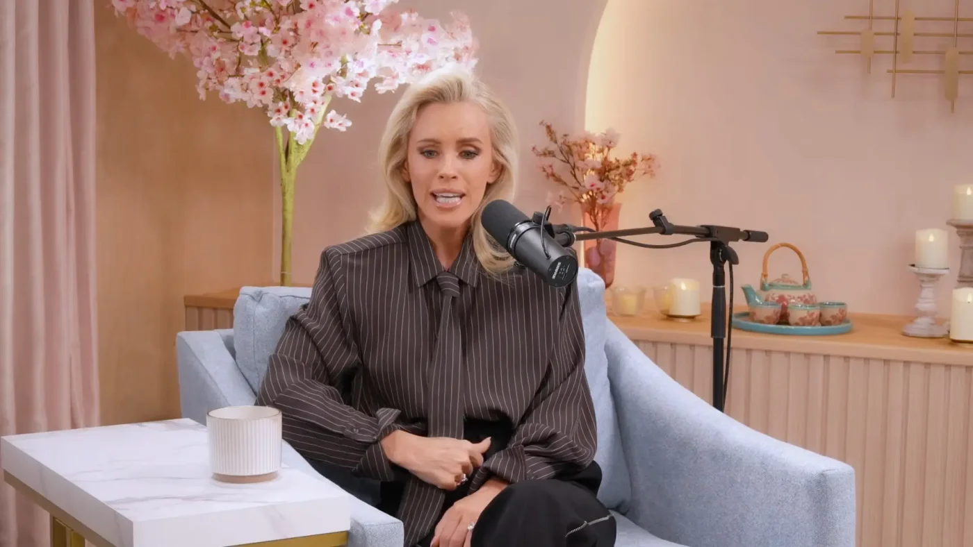 Jenny McCarthy sits in a blue armchair in a podcast studio with a microphone in front of her.
