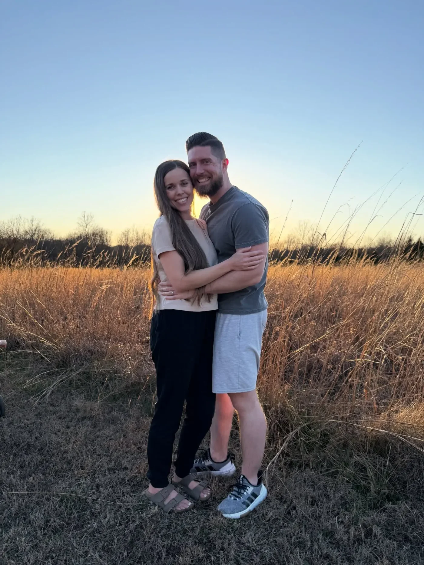 Jessa Duggar and Ben Seewald pose together in a field at sunset.