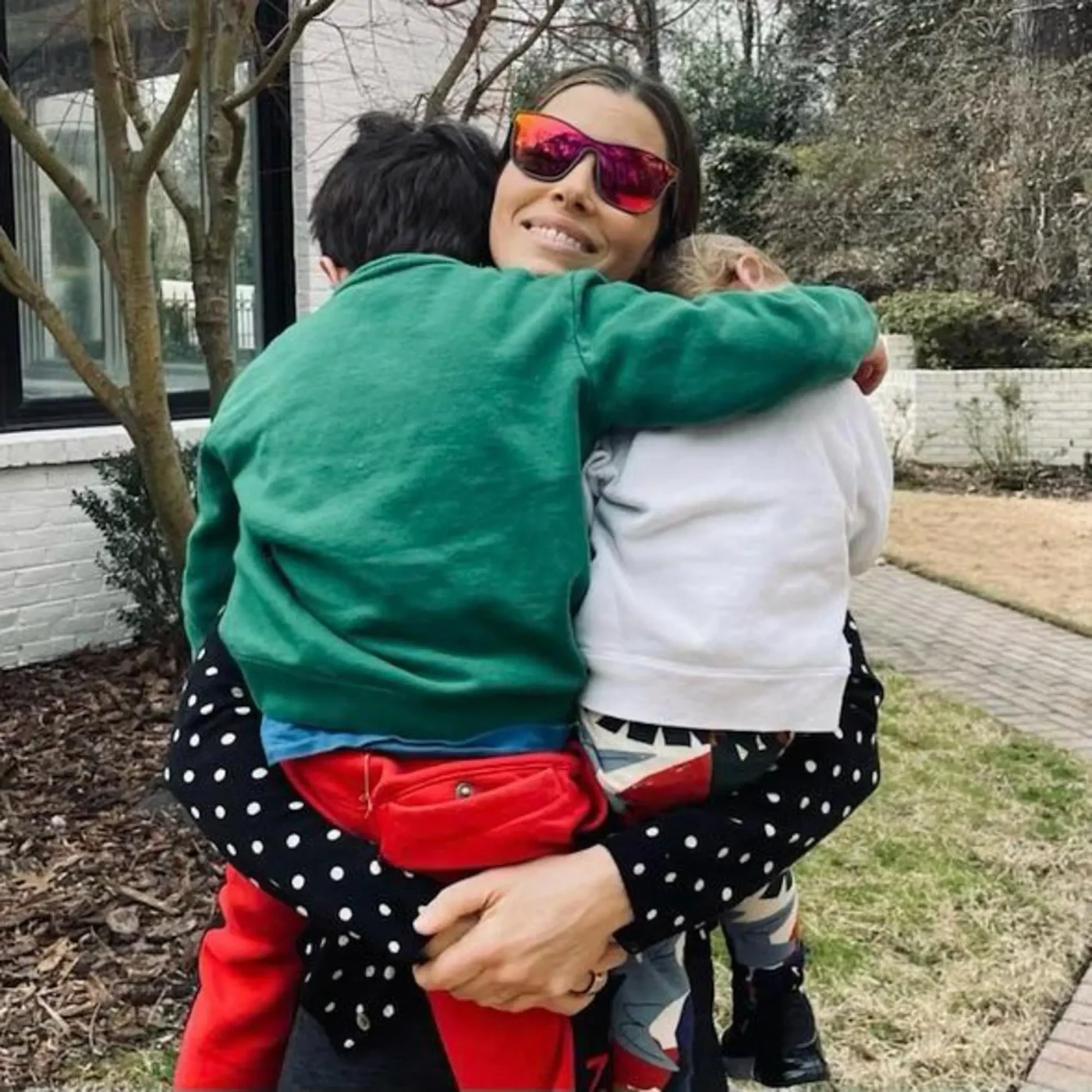 Jessica Biel embraces her children, Silas and Phineas, outdoors.