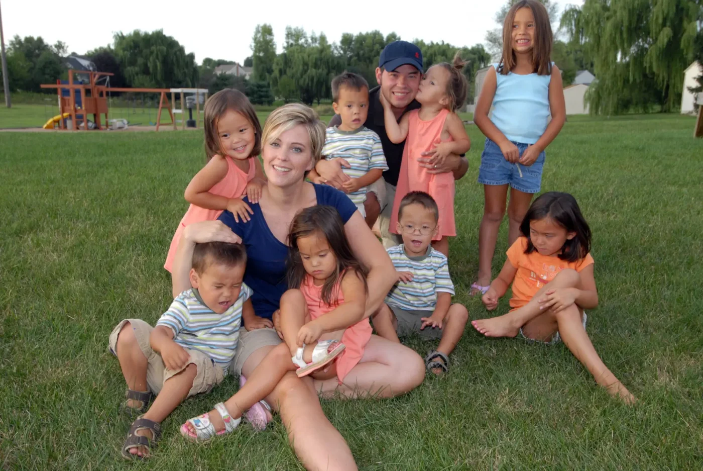 Jon and Kate Gosselin and their eight children pose together outdoors on a grassy lawn.