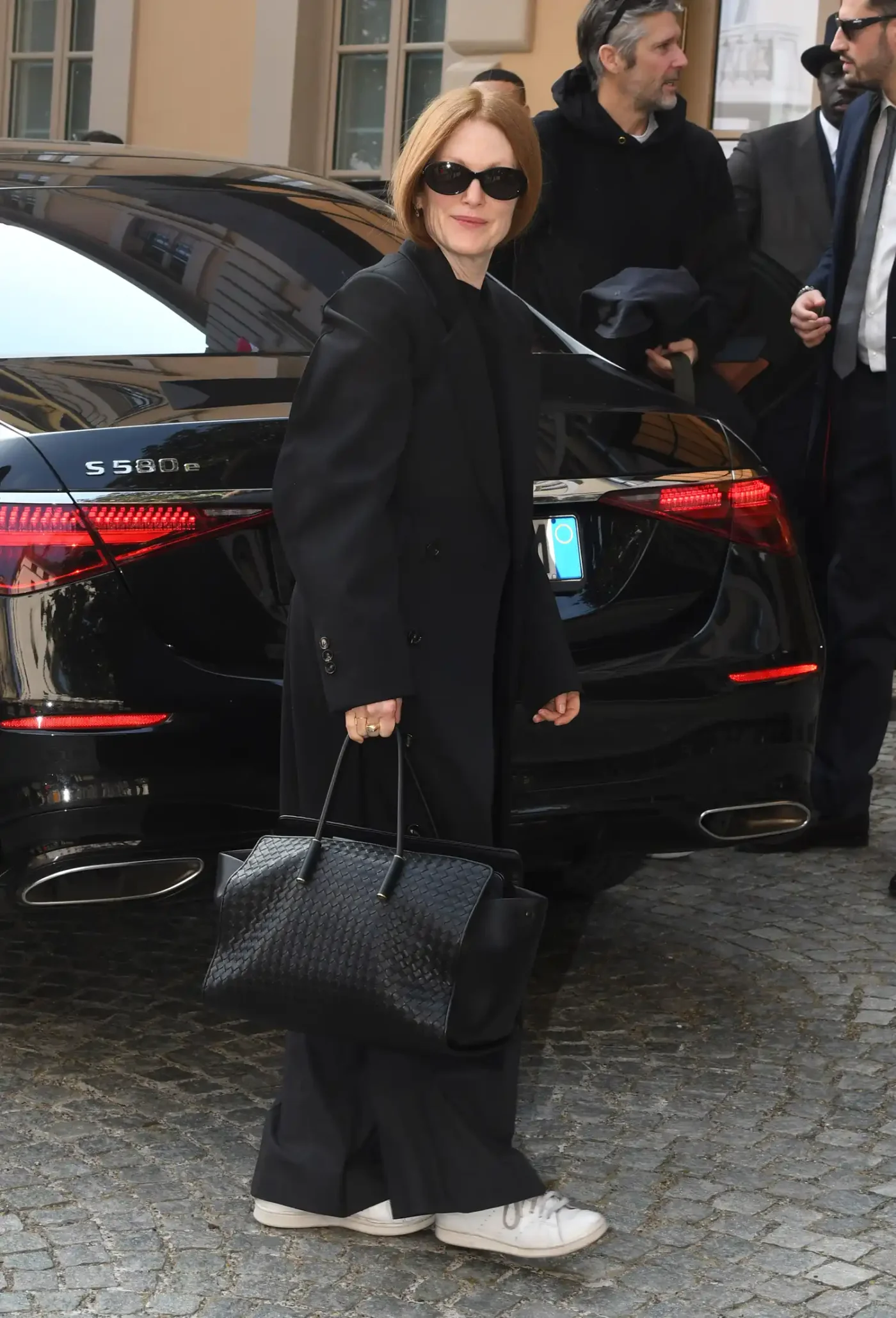Julianne Moore walking outside carrying a handbag with a car in the background