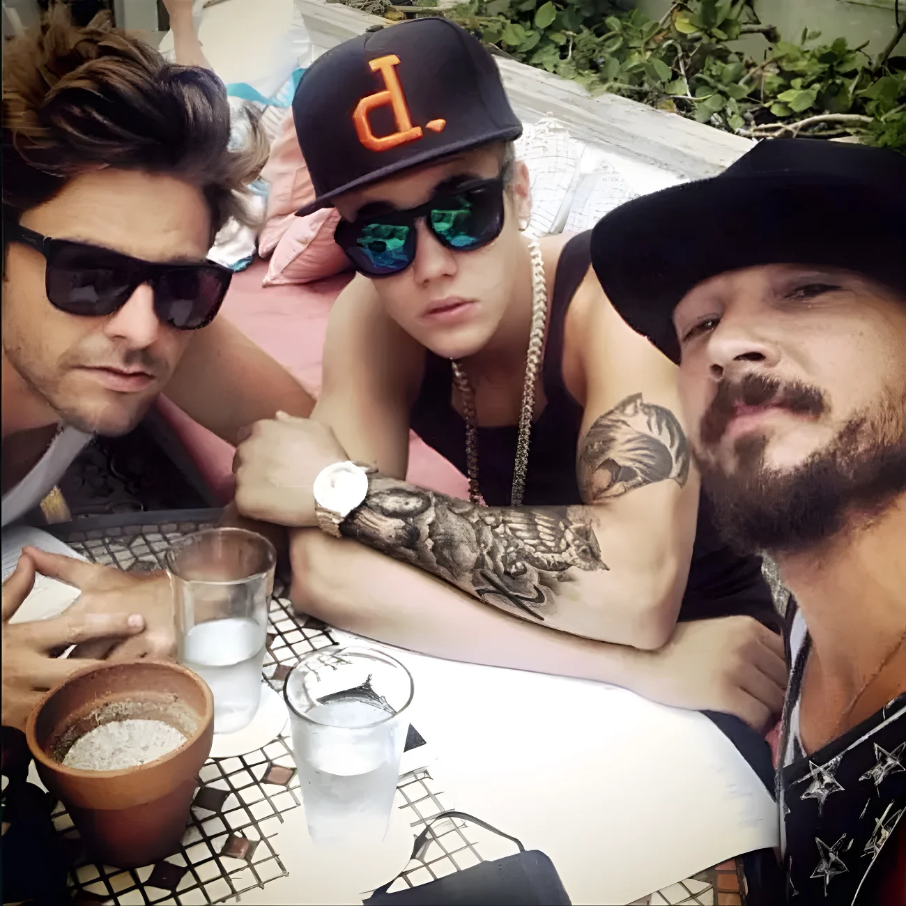 Justin Bieber, Hillsong NYC Pastor Carl Lentz and Ryan Good sitting at an outdoor table.