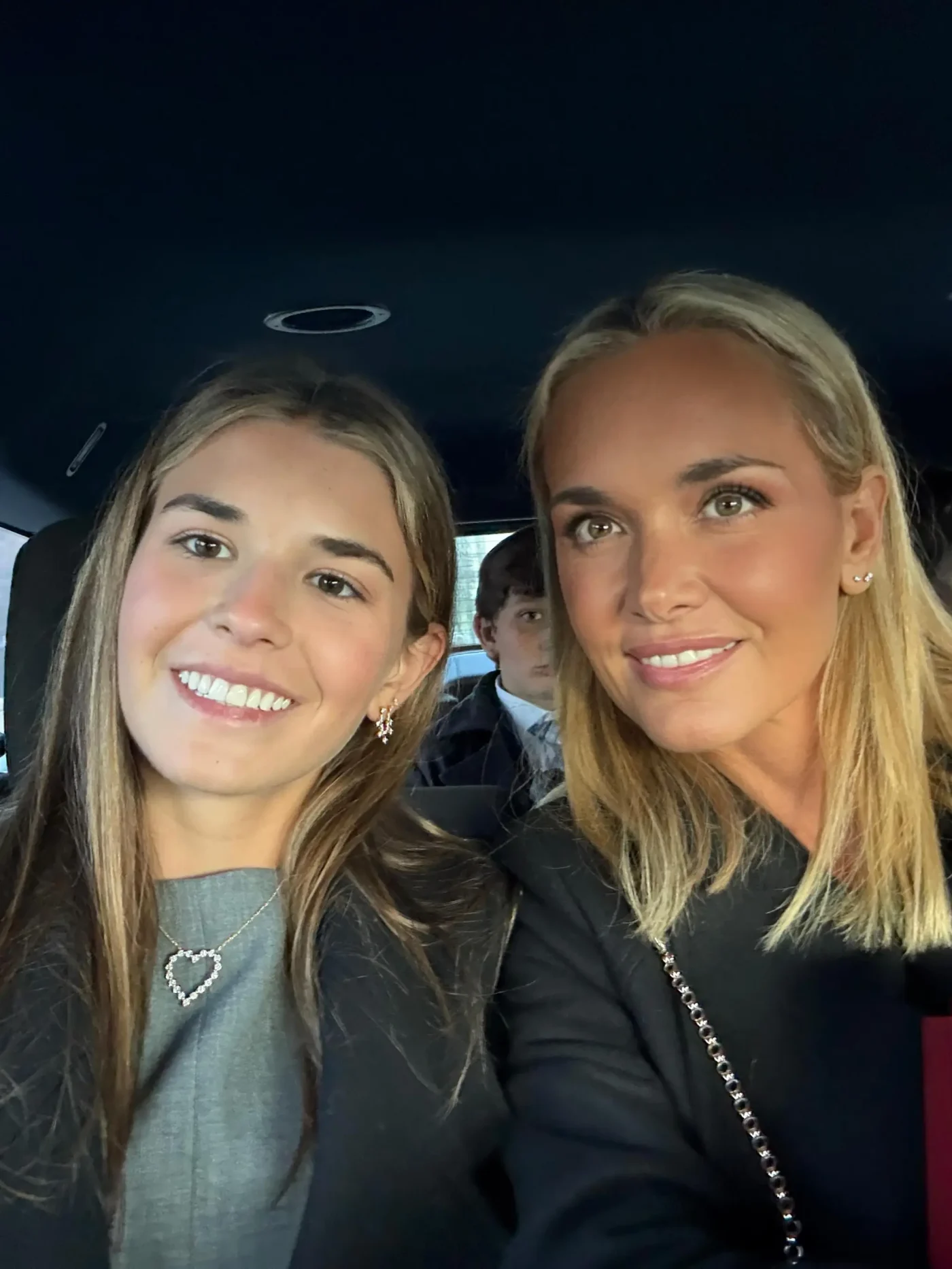 Kai and Vanessa Trump smiling in the back seat of a car, with a young boy visible in the background.