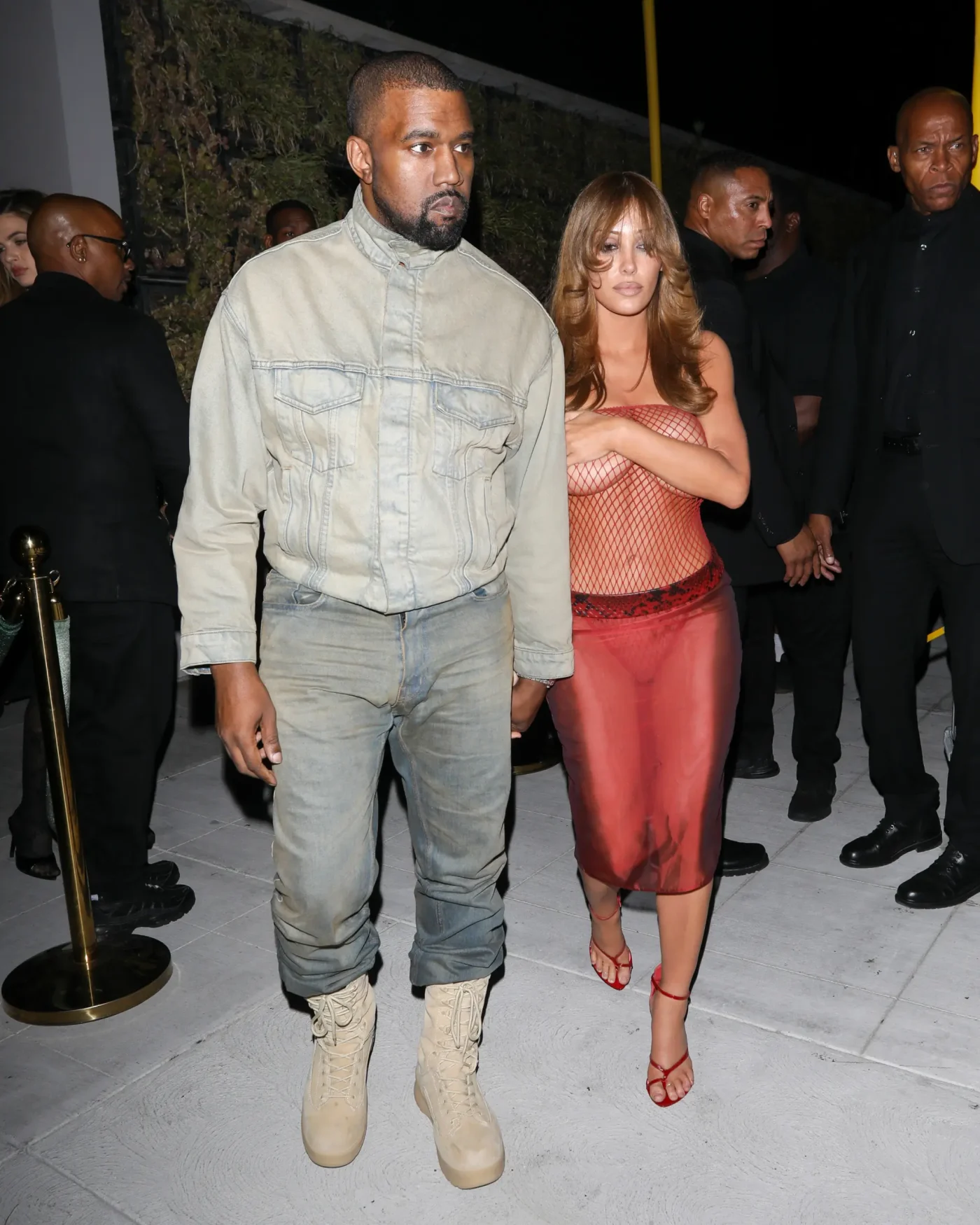Kanye West and Bianca Censori leaving a club in Los Angeles, with Bianca wearing a red fishnet top.