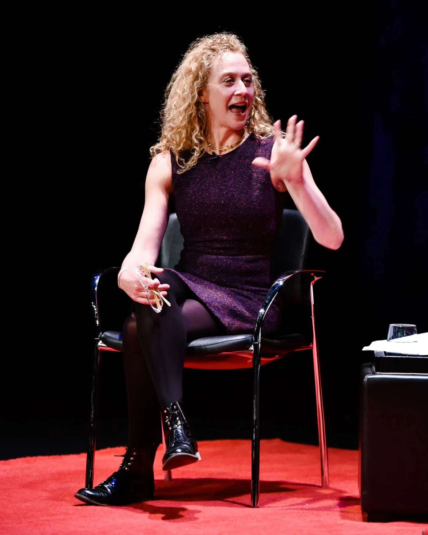 Katie Rosman sits on a stage, gesturing while speaking.