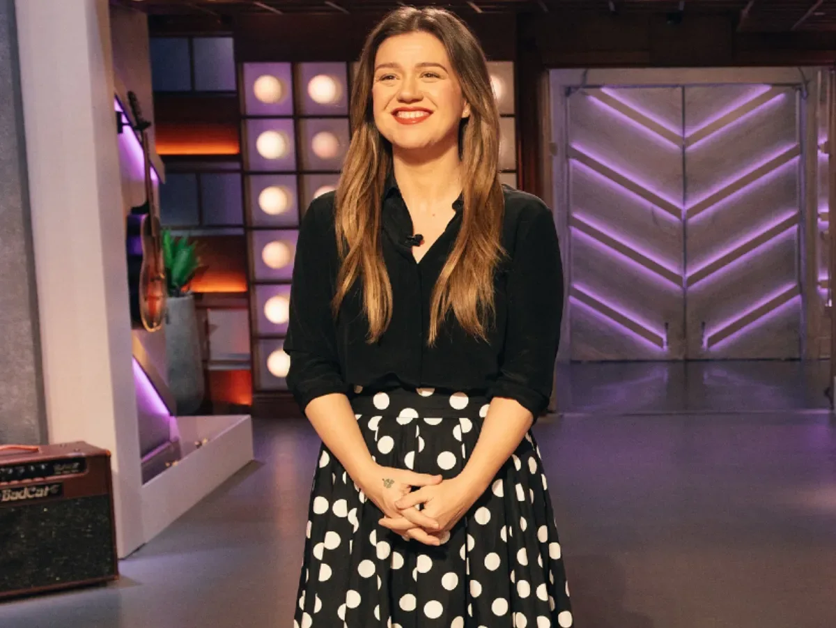 Kelly Clarkson smiles as she stands on the set of