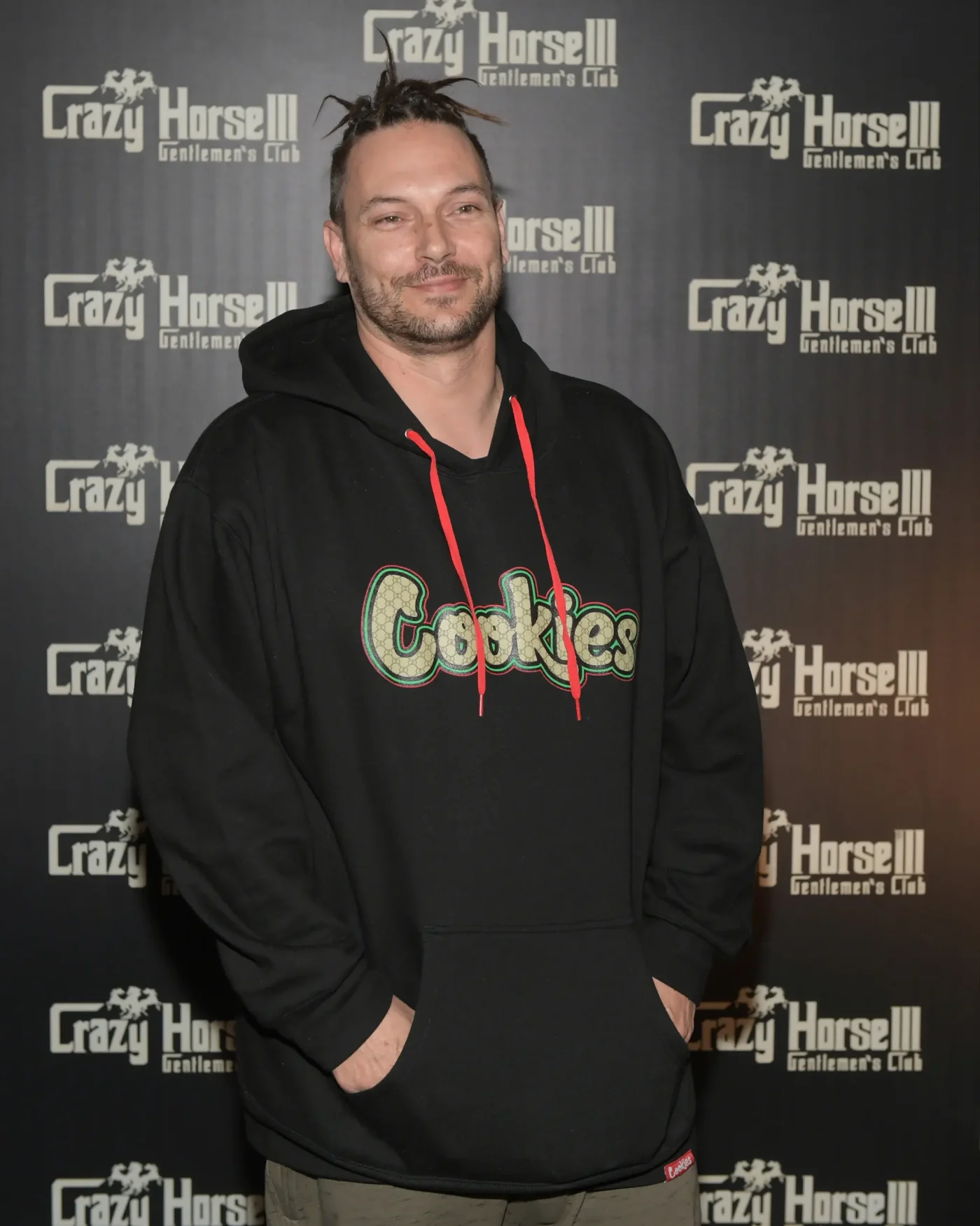 Kevin Federline wearing a black hoodie in front of a branded backdrop.
