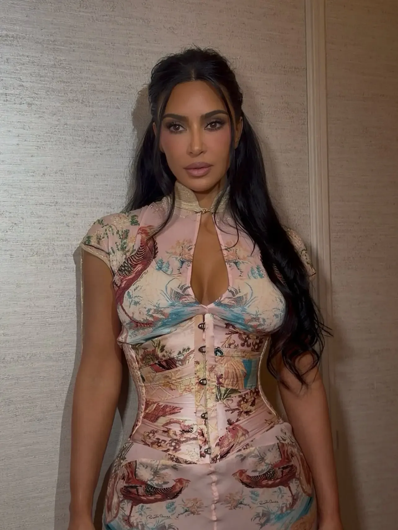 Kim Kardashian wearing a pink, printed dress with a corset top and high neckline.