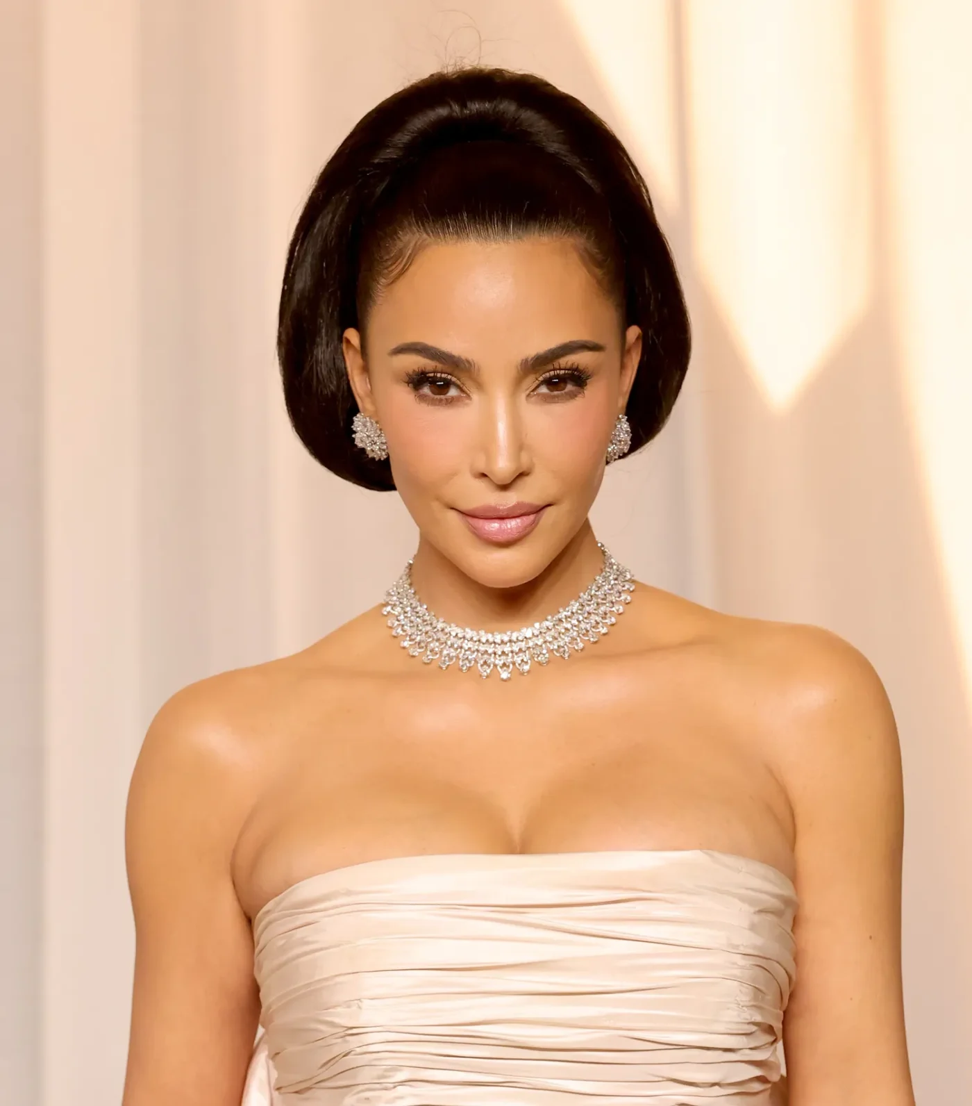 Kim Kardashian with a retro updo and off-white lace gown at an event