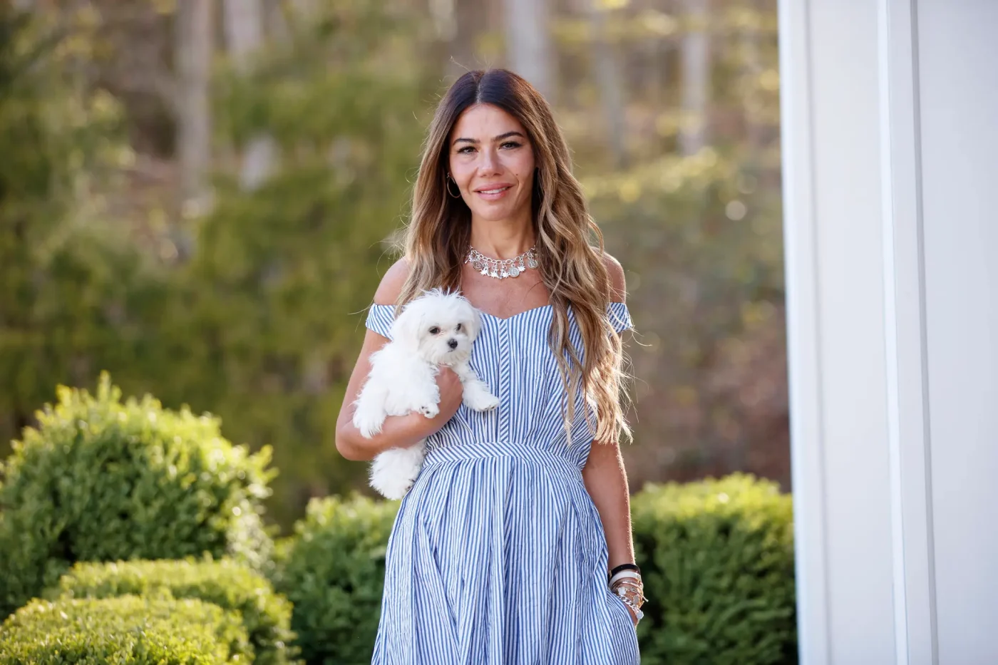 Libbie Mugrabi holding a small white dog outside her Watermill home.