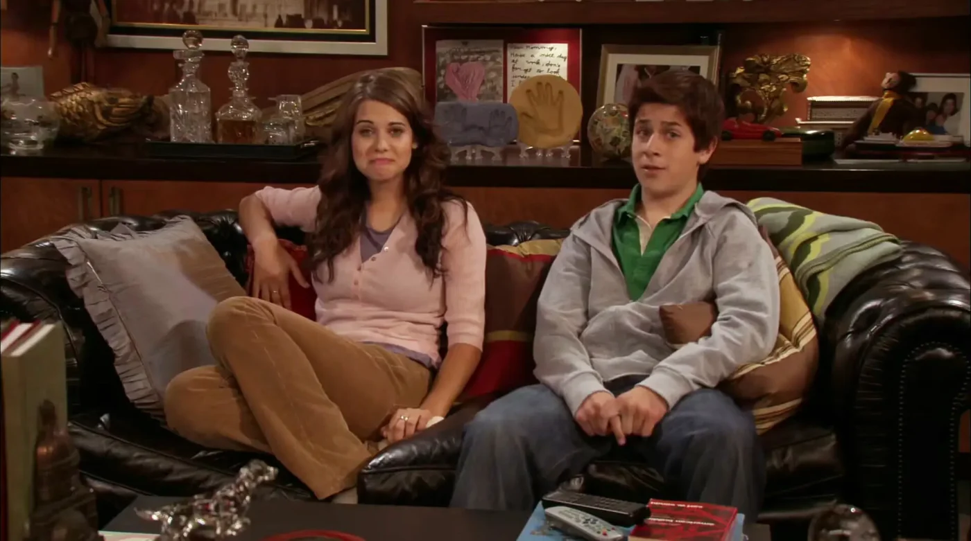 Lyndsy Fonseca and David Henrie playing Luke and Penny Mosby sitting on a couch in How I Met Your Mother.