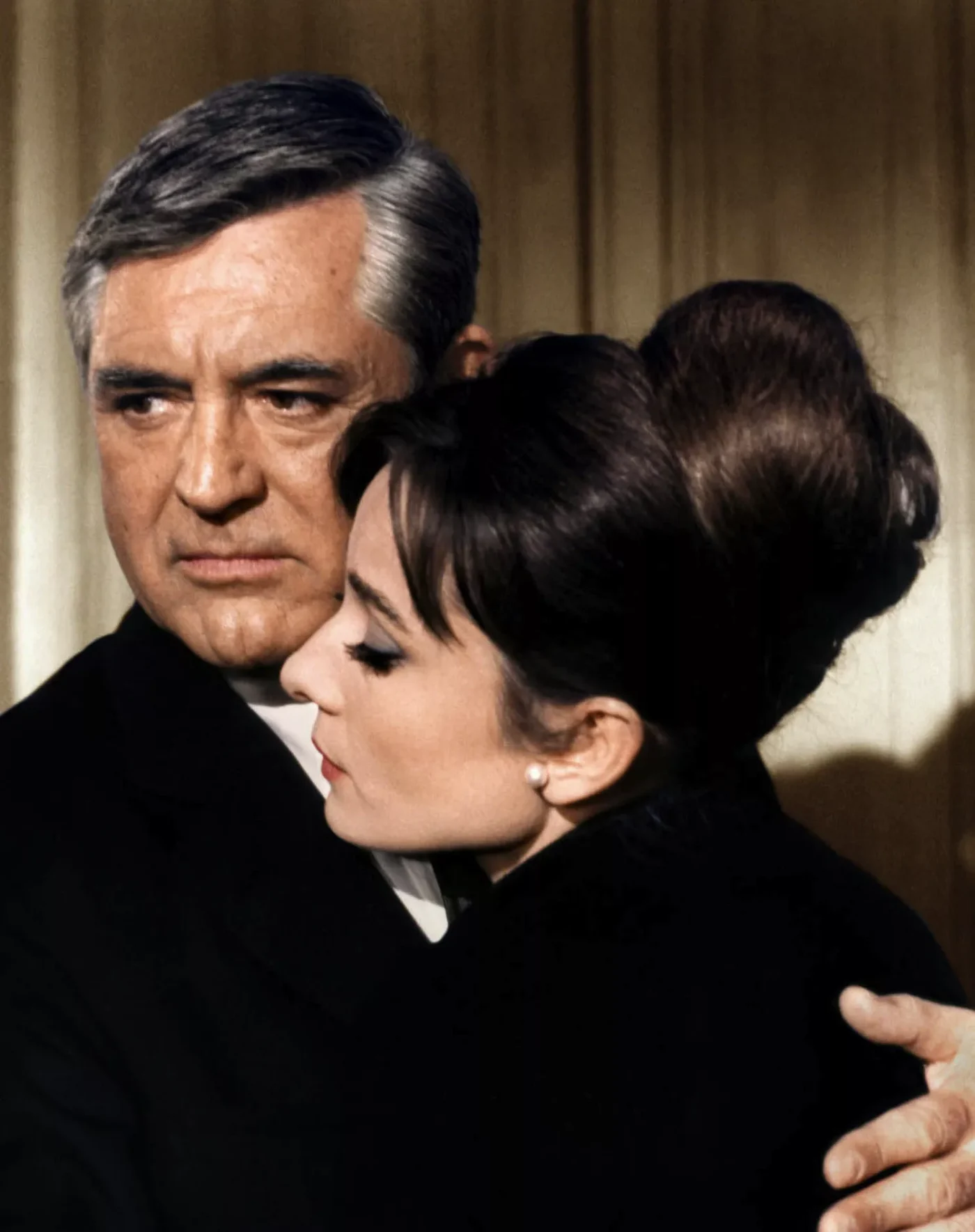 Man hugs Audrey Hepburn while she wears a chignon hairstyle