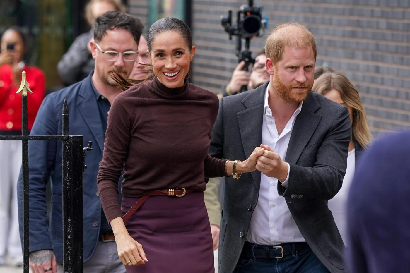 Meghan, Duchess of Sussex, and Prince Harry, Duke of Sussex, walking together and holding hands.
