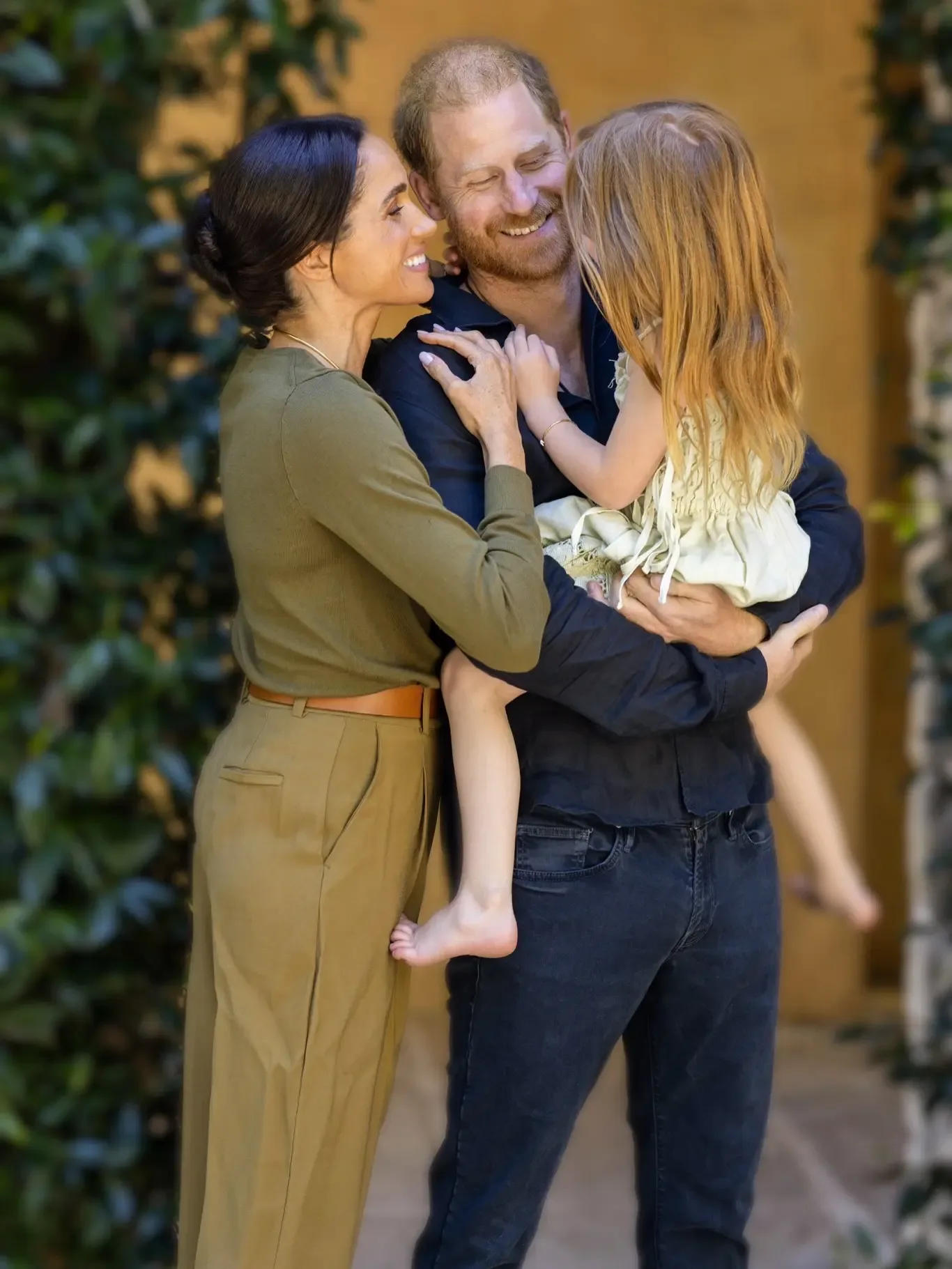 Meghan Markle and Prince Harry smiling as he holds Lilibet.