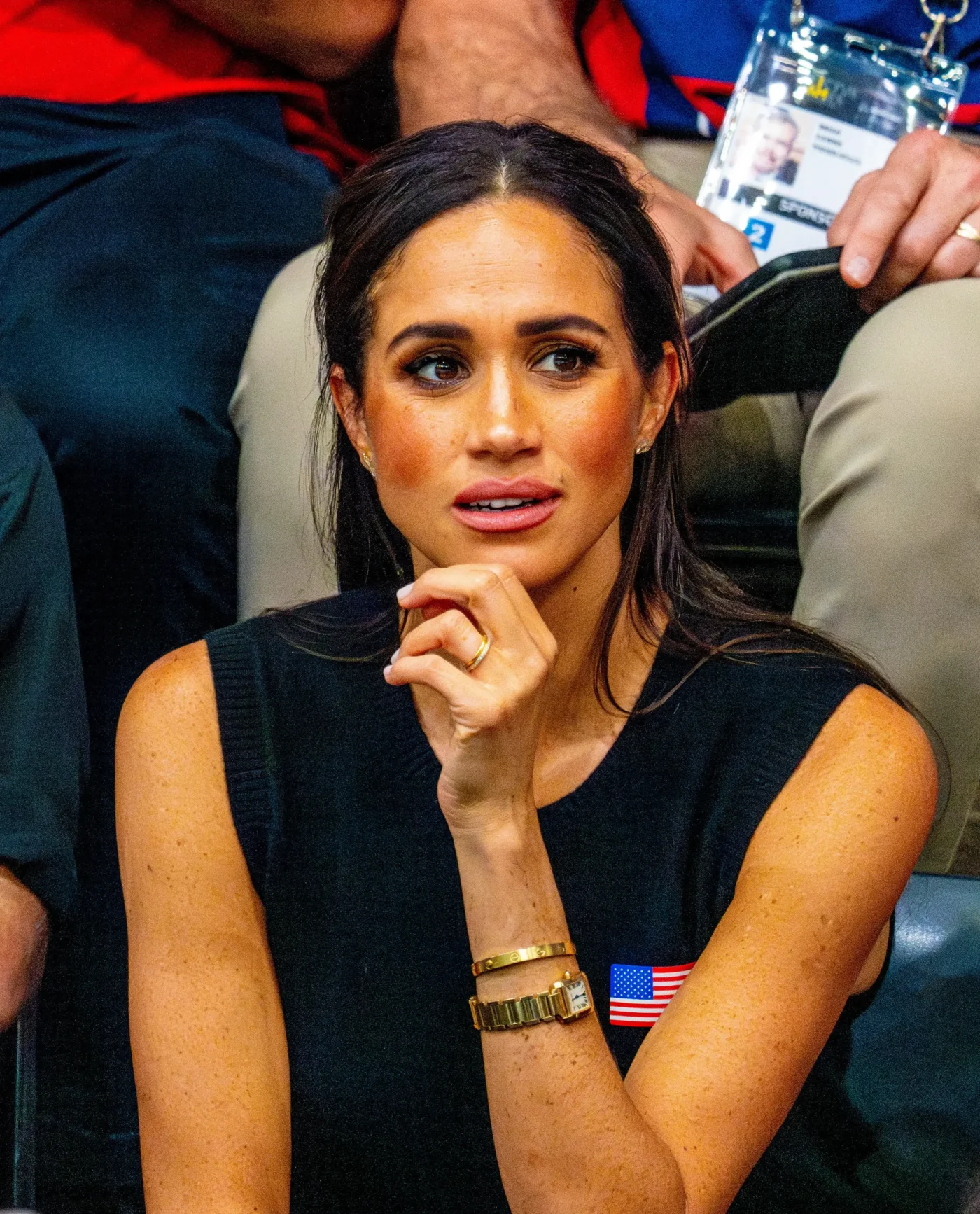Meghan Markle seated in the audience with her hand near her chin.