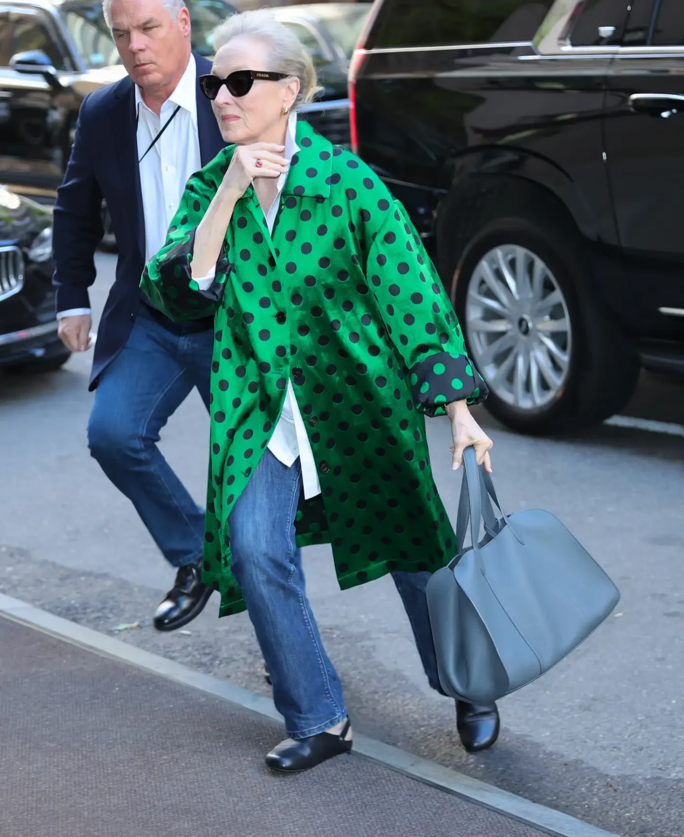 Meryl Streep walking on a street holding a bag wearing sunglasses