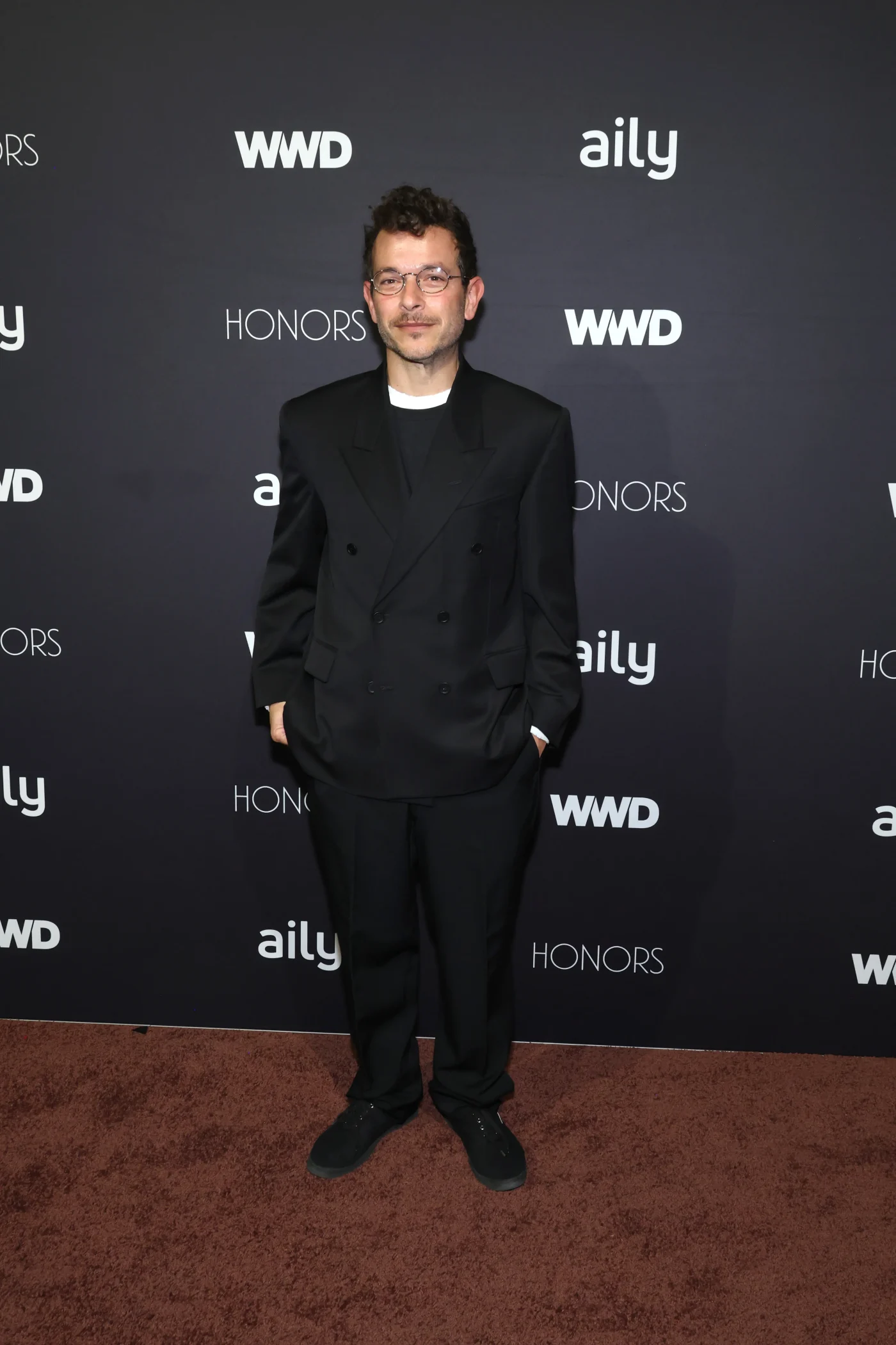 Michael Rider stands in front of a step-and-repeat backdrop at the 2026 WWD Honors.