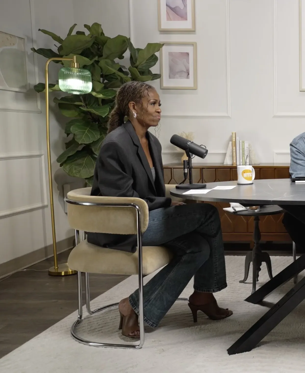 Michelle Obama seated at a table speaking into a microphone