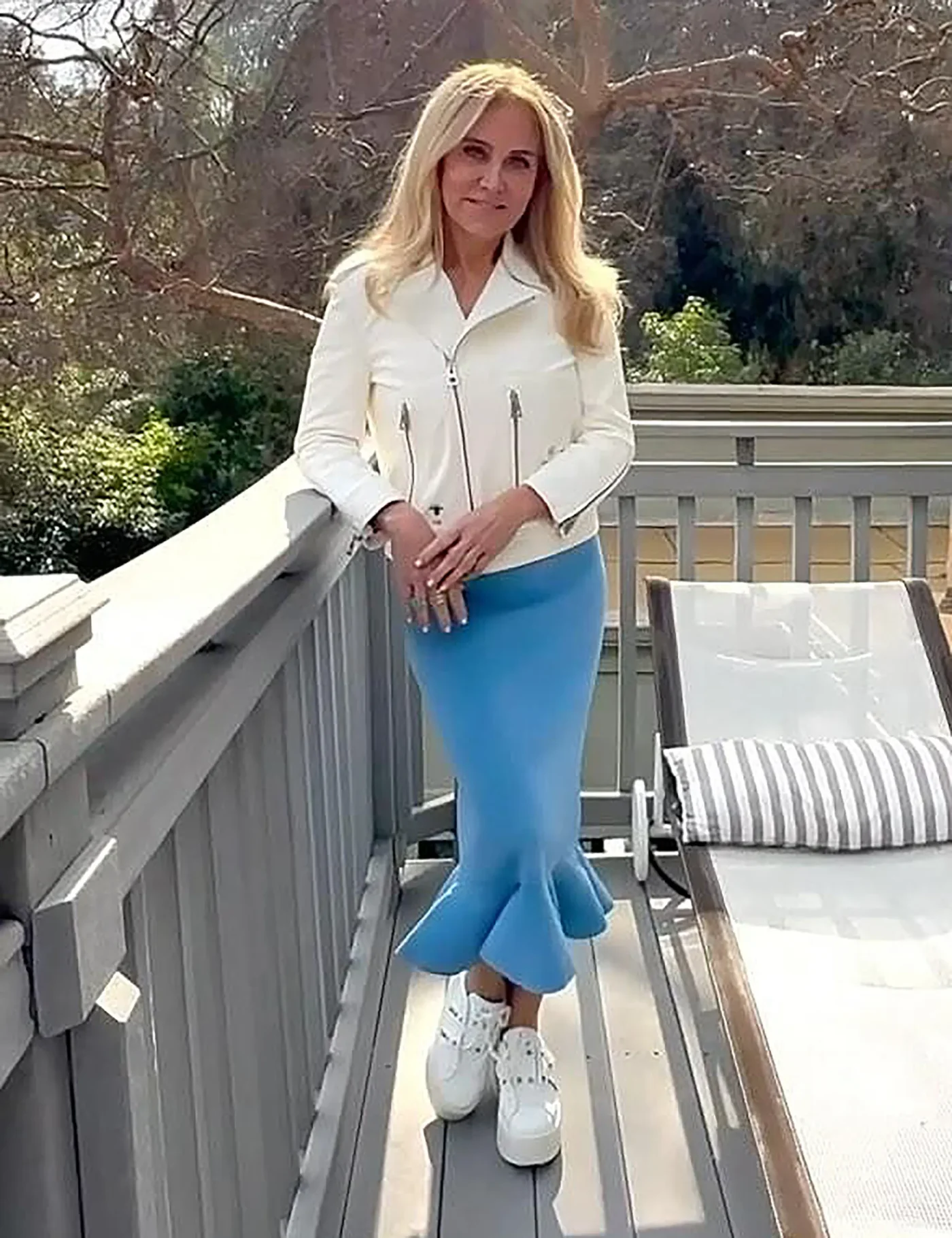 Monet Berger standing on a deck in a white jacket and blue skirt.